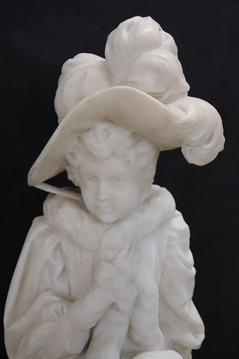 Questa squisita scultura italiana in marmo bianco di Carrara cattura l'essenza di una giovane donna della fine del XIX secolo con notevole precisione e maestria. L'attenzione ai dettagli del suo abbigliamento elegante, che suggerisce il suo