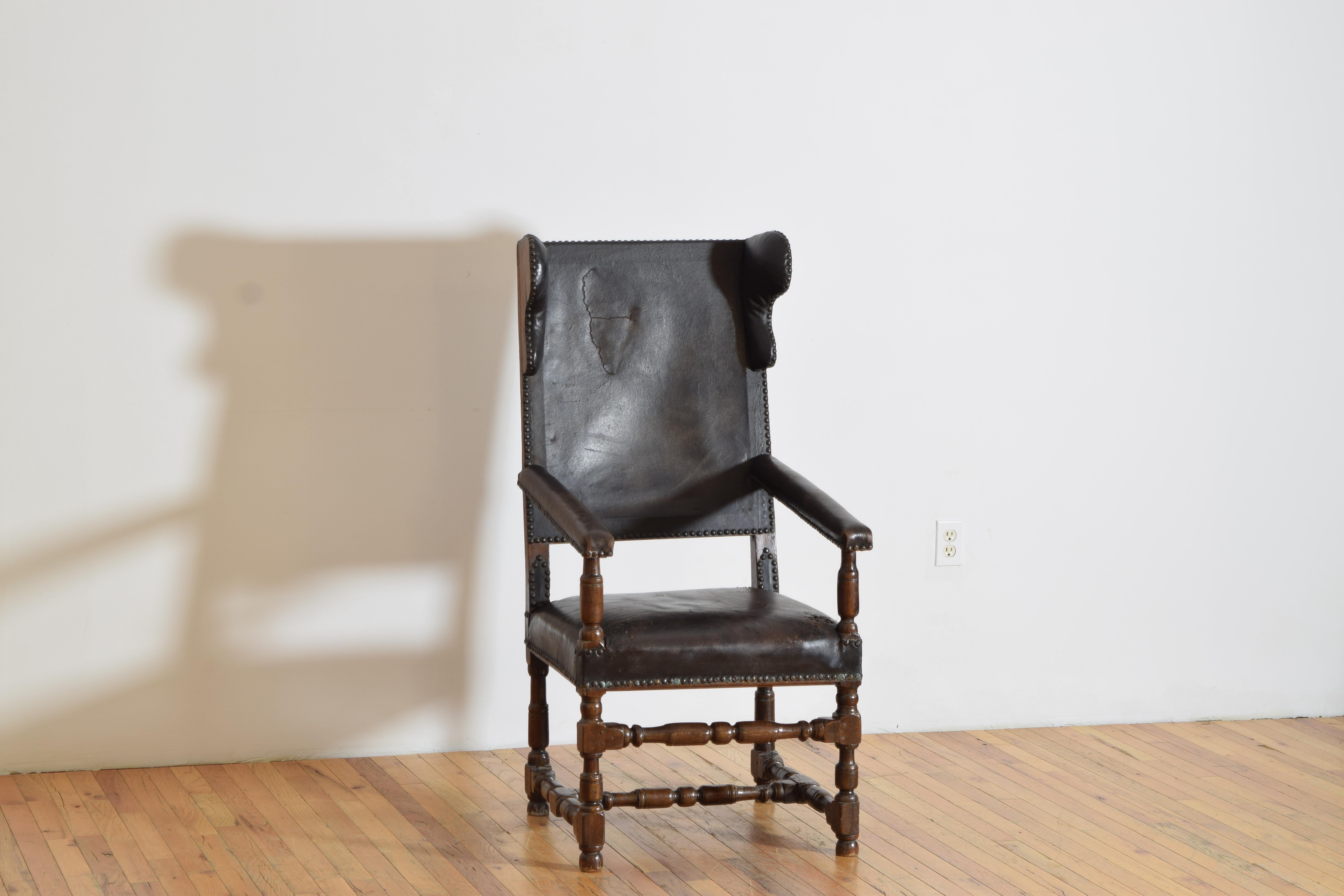 L'assise, le dossier, les accoudoirs et les ailes sont recouverts de cuir. Cette chaise est construite en bois massif avec des supports d'accoudoirs, des pieds et des brancards tournés.