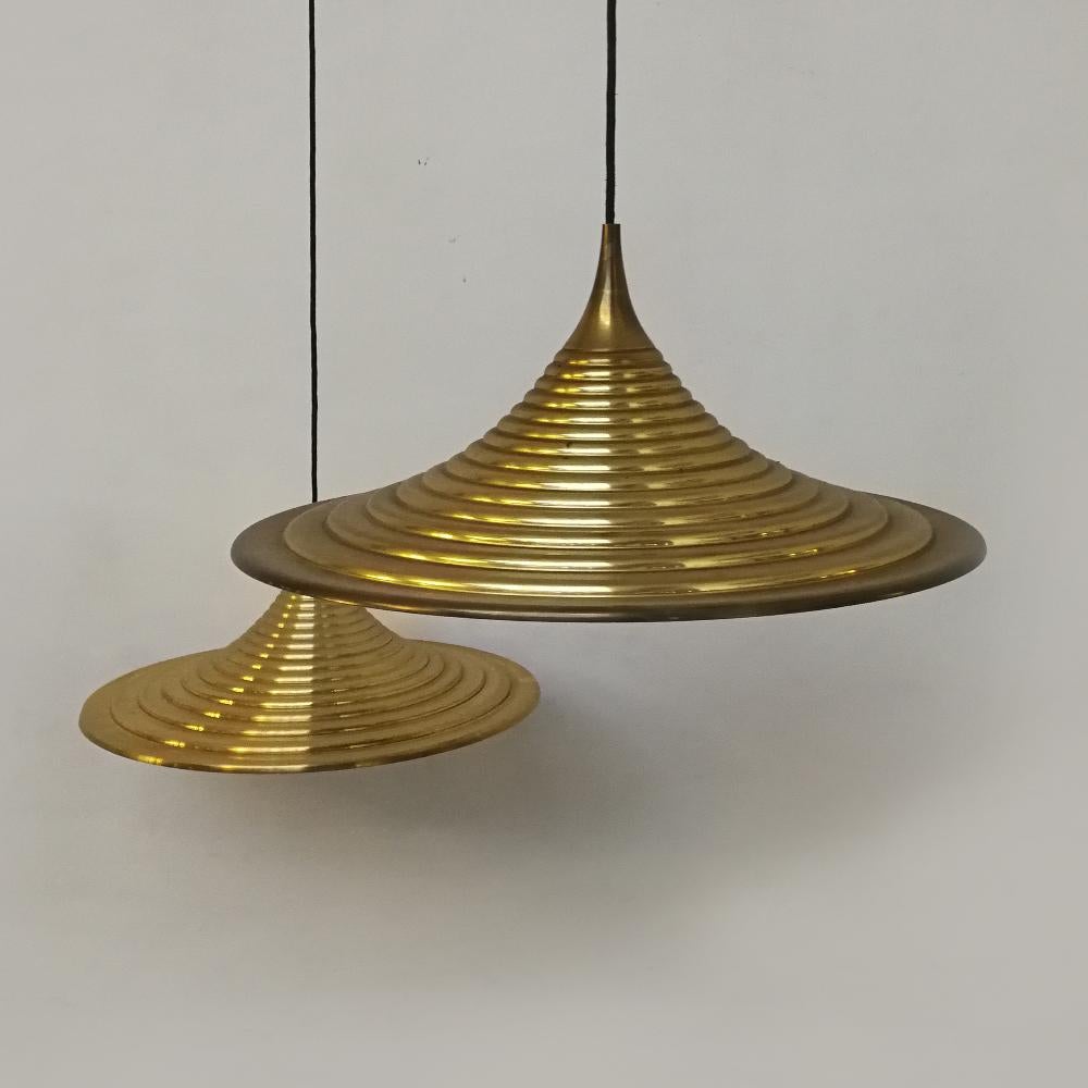 Italian lathed metal brass finishing hanging lamps, 1970s
Couple of exclusive brass hanging lamp, probably dating to the Italian 1970s production, provided of a bell sinuous shape, in lathed metal, brass finishing outside and ivory white painted