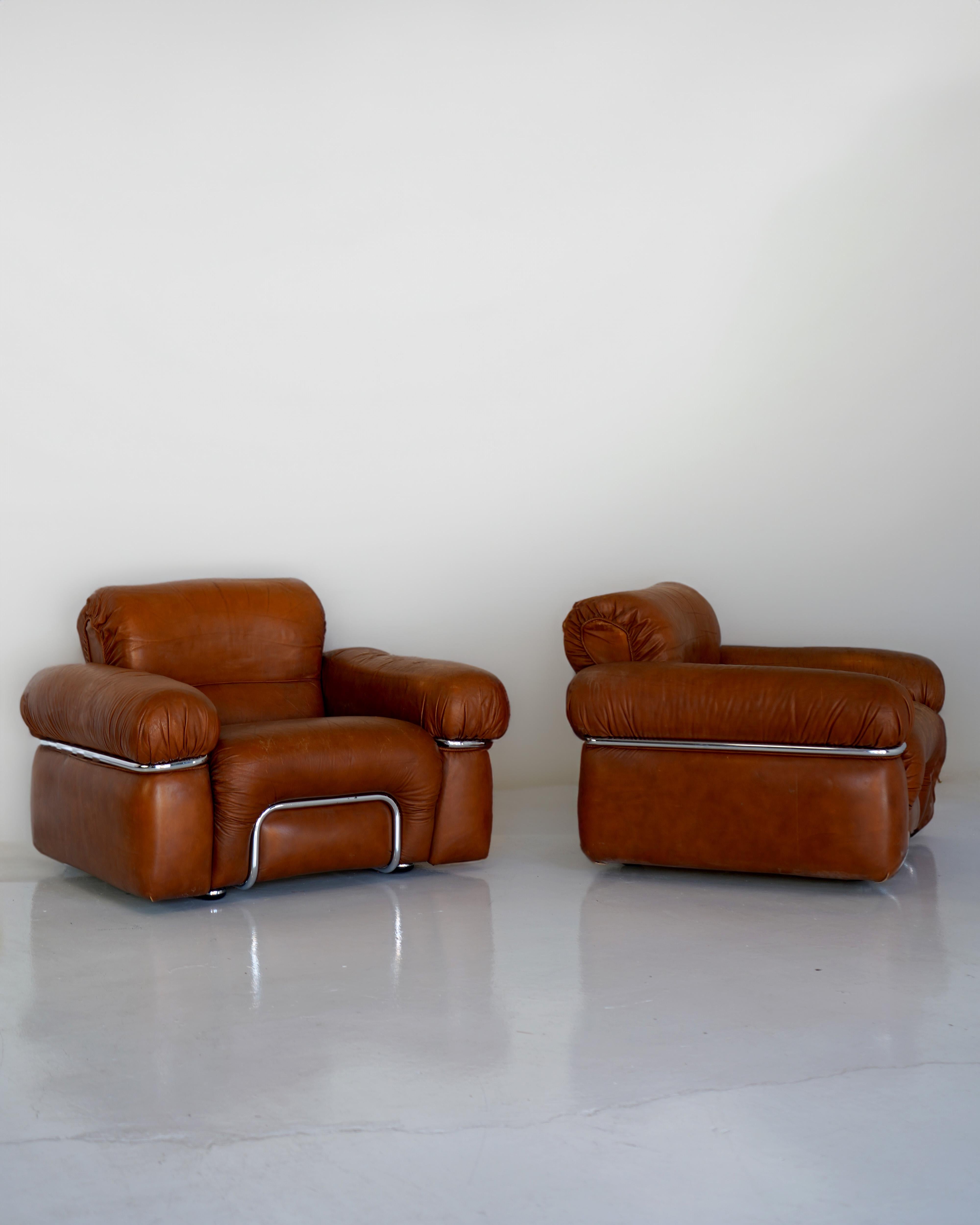 Chunky curves enveloped in cognac Italian leather and wrapped in chrome. These Adriano Piazzesi attributed armchairs epitomize the allure of 1970s Italian design.

In good condition. Sold as a pair.