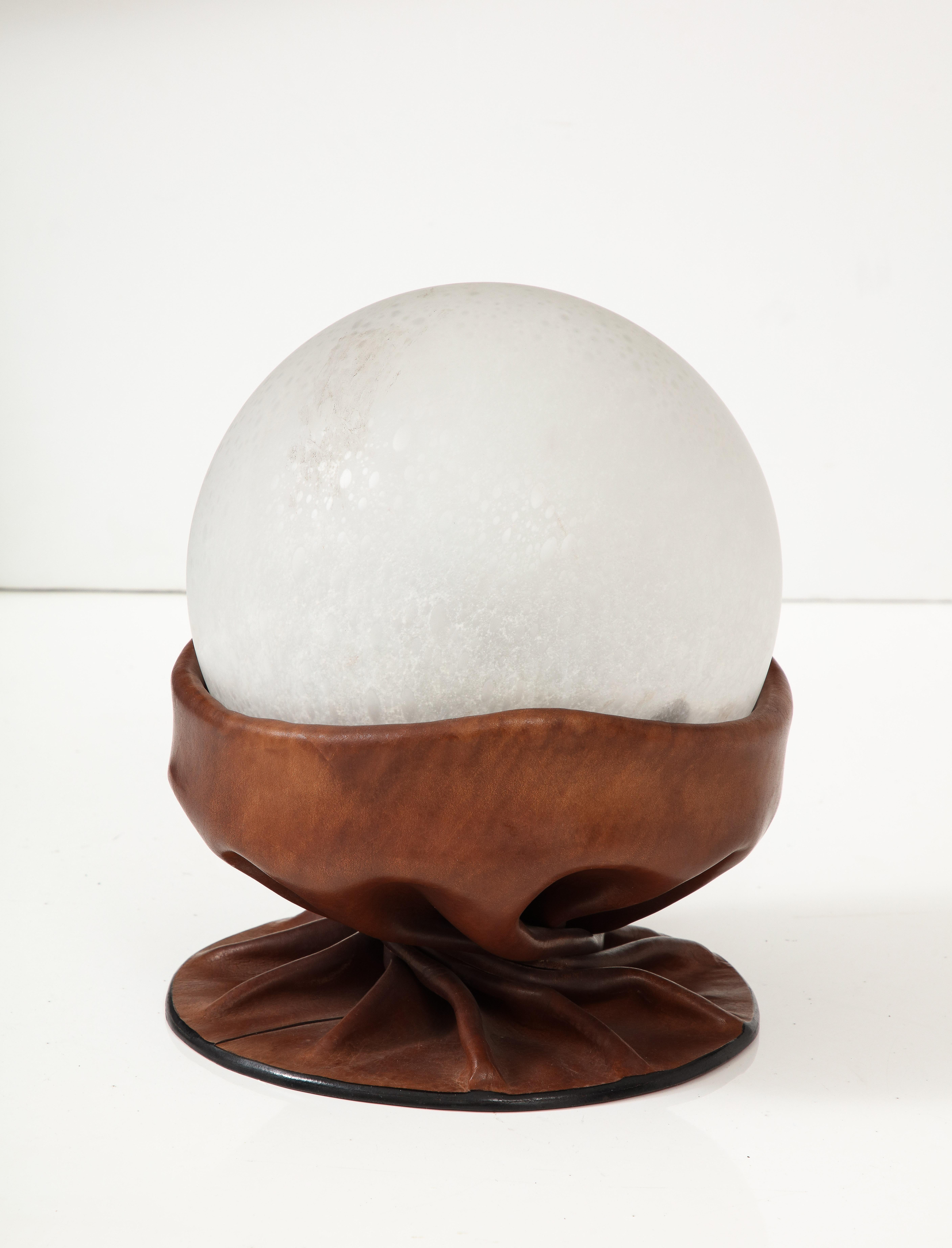 Italian space age leather and glass table lamp, the draped warm brown leather base supports a mottled hand-blown glass orb. Emits a wonderfully warm glow.
by Nova Tecno, Italy, circa 1960's
Size: 12 1/2