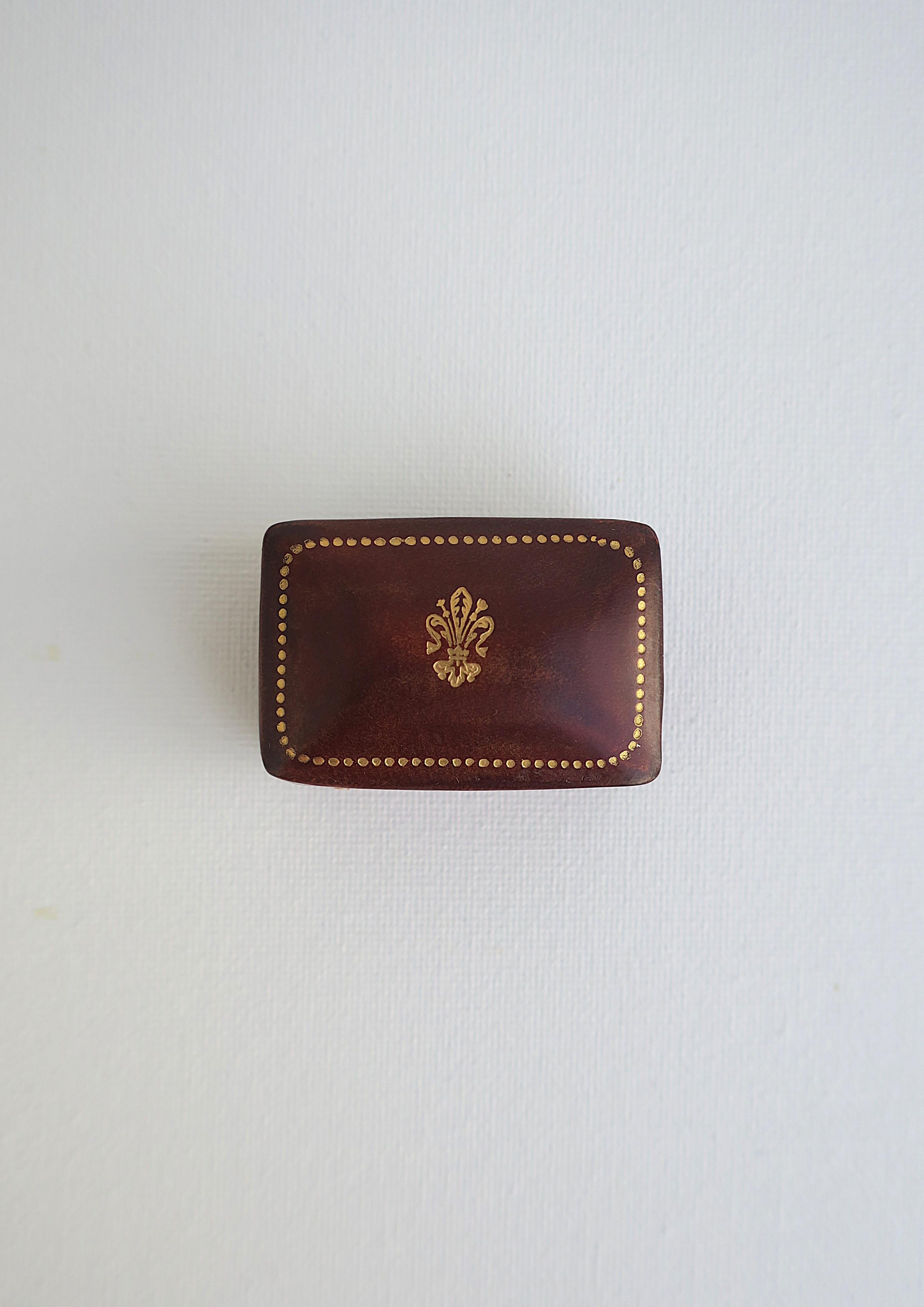 Caja italiana de cuero marrón con repujado dorado, hacia mediados del siglo XX, Italia. Pequeña caja rectangular de piel italiana con un diseño de flor de lis en la tapa superior y puntos dorados alrededor. Marcado en la parte inferior como se