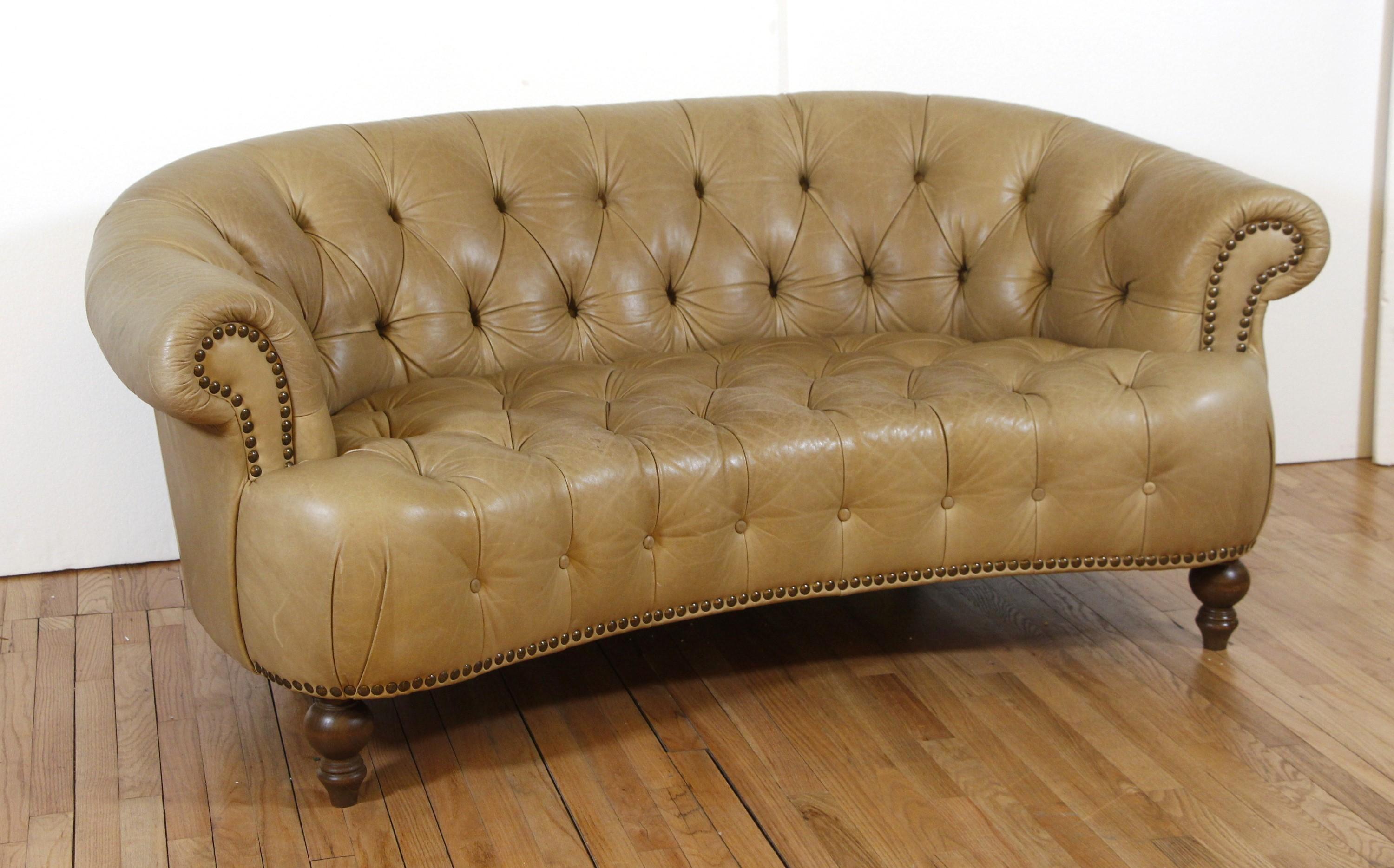 Italian made tan tufted leather sofa with curved back. This Chesterfield style sofa has nailheads throughout and stylish wooden feet. Tan - 73 in.

 