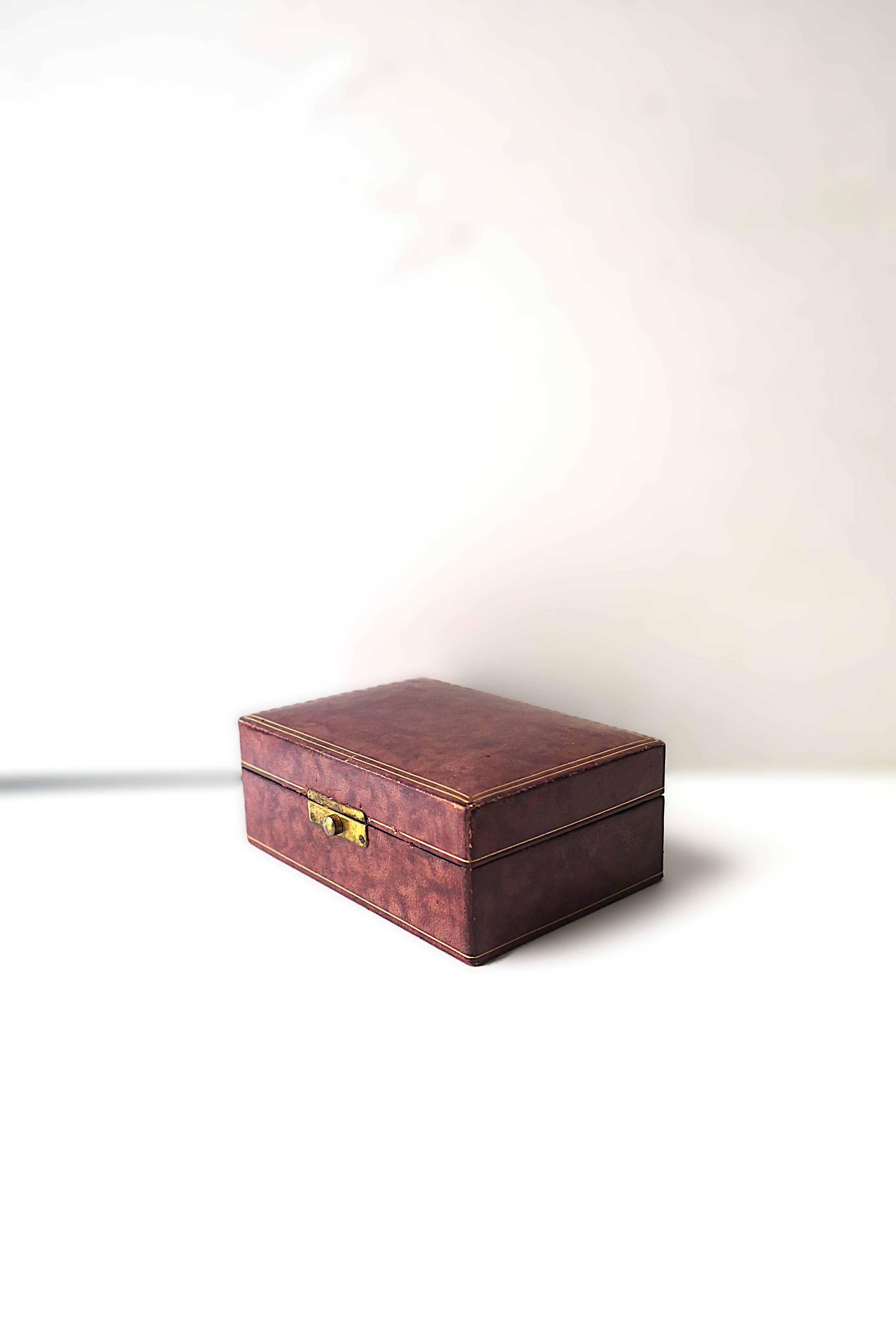 Joyero italiano de cuero repujado en color berenjena (berenjena clara) y dorado, con cierre de latón, hacia mediados del siglo XX, Italia. La caja tiene un interior de ante con una zona para anillos (demostrada) y otras joyas (mostrada sosteniendo