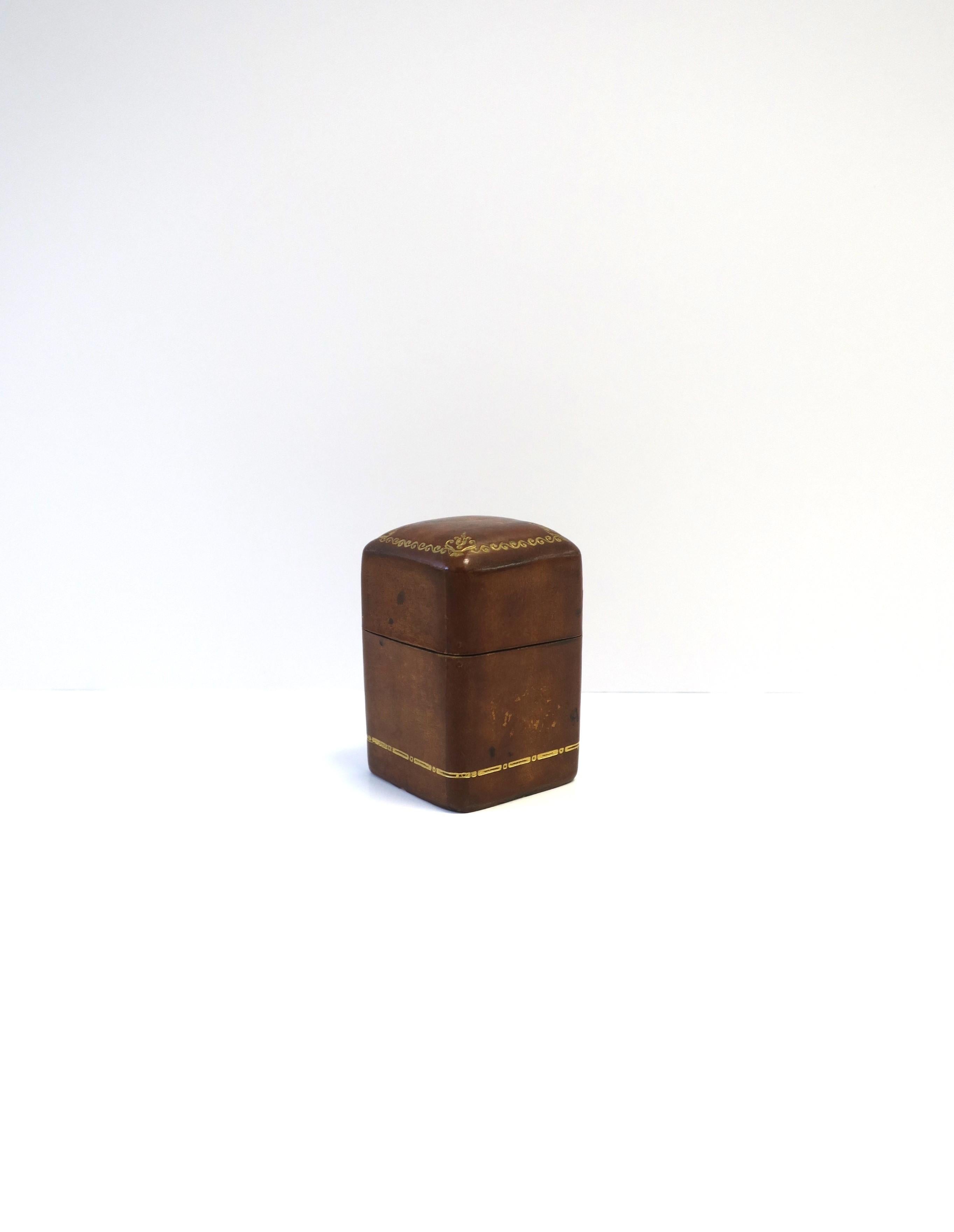 A beautiful Italian leather and gold embossed matchstick holder box and match striker, circa mid-20th century, Italy. This Italian leather piece has gold embossed detail on top lid and around bottom base. Striker area on bottom. Great for tobacco