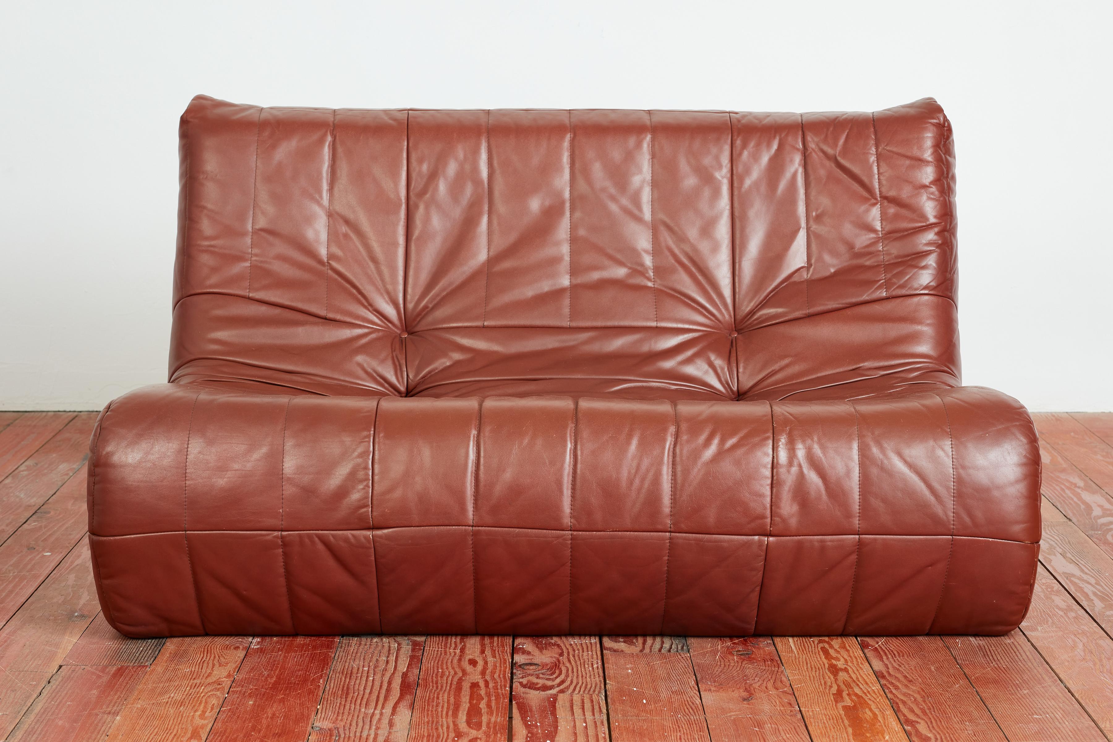 1970's Italian leather settee in the style of a TOGO- with foam core and wrapped with cognac colored leather with vertical stitching. 
Italy, 1970's

Matching sofa available 