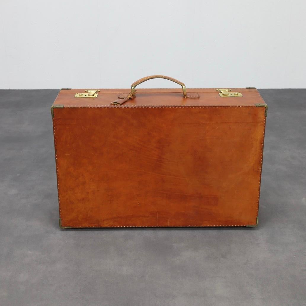 Una rara valigia in pelle italiana realizzata a mano negli anni '60, attribuita a Ferrari. Realizzato con una notevole maestria artigianale, questo pezzo è caratterizzato da una spessa pelle da sella, angoli rinforzati in ottone e dettagli cuciti a