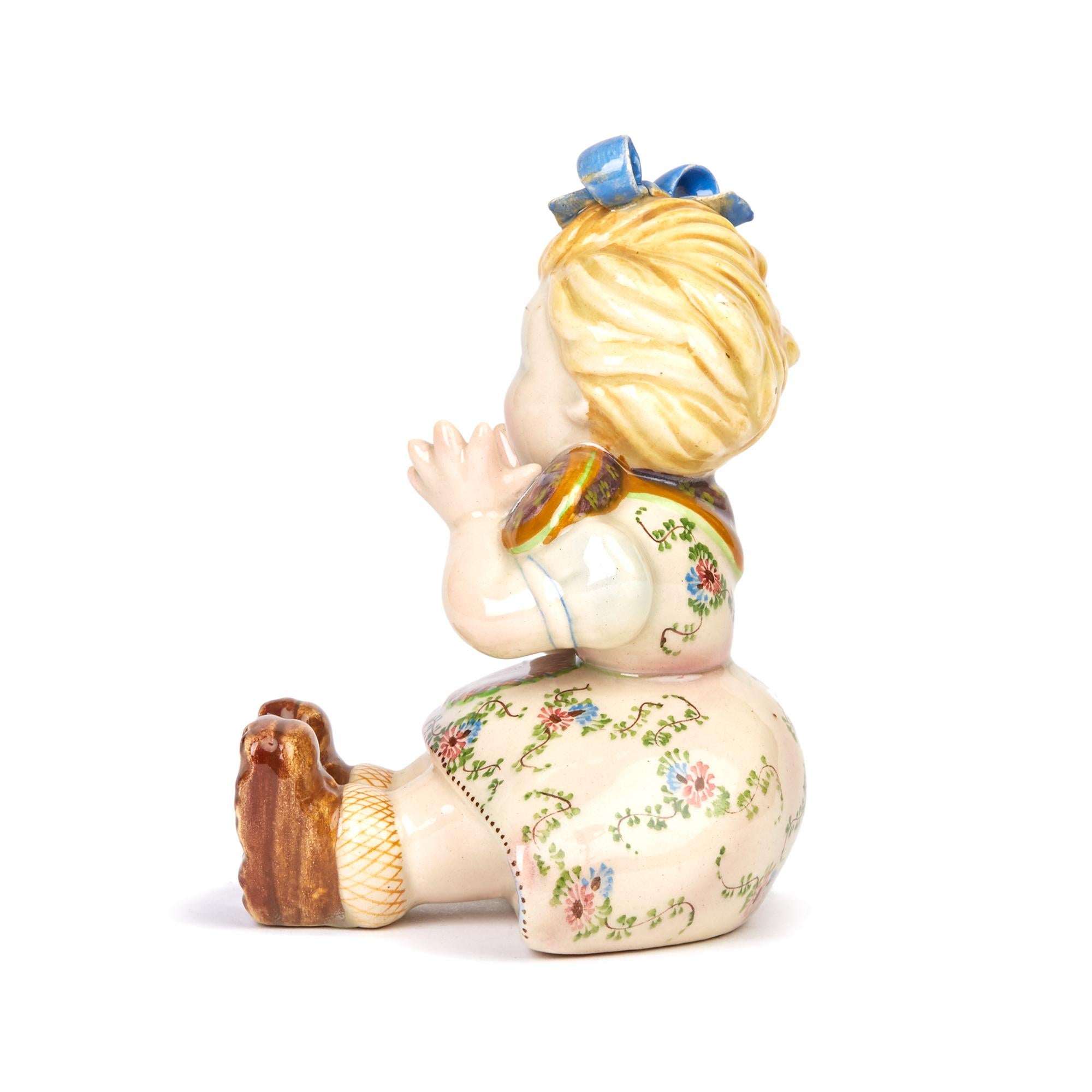 A charming quality Italian art pottery figure of a seated girl singing in the style and quality of Lenci dating, between 1930-1950. The figure sits wearing a floral painted dress and large blue painted bow to the hair and is finely hand painted in