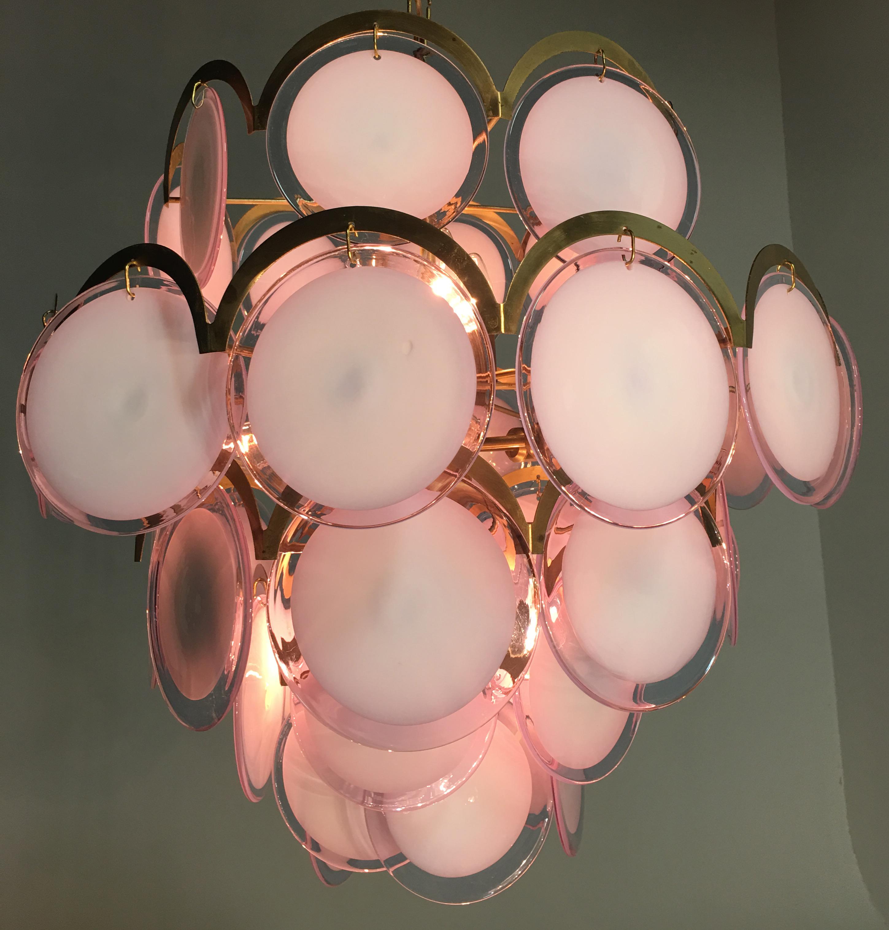 Spectacular pair of chandeliers by Vistosi made of 41 Murano discs honey color on five floors. The characteristic of these glasses is that they change with the changing of light. From white to natural light to a pale blue with neon light to pink