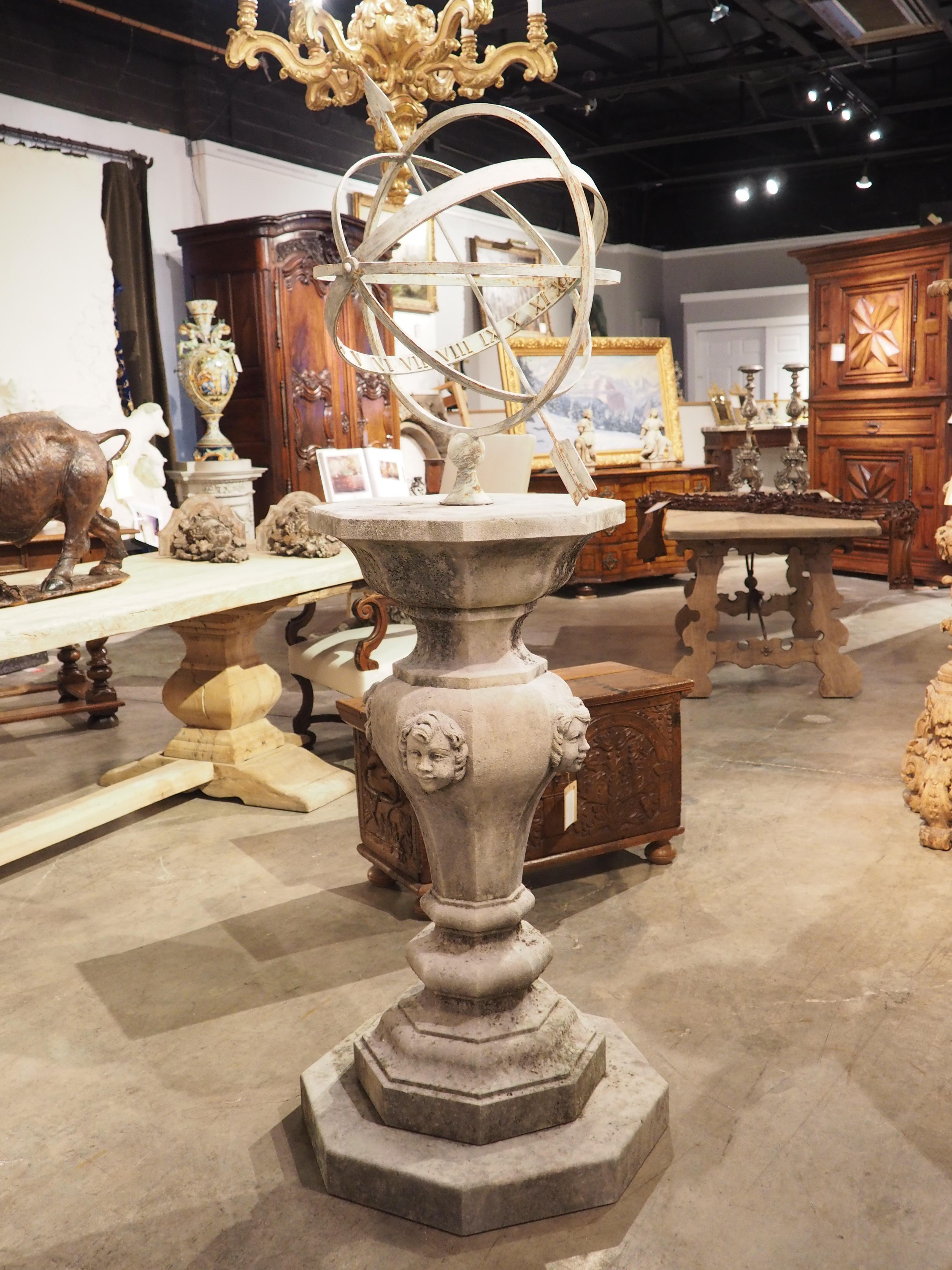 Hand-carved in Italy, this limestone armillary sundial features an octagonal step beneath a column adorned with putti mascarons. Both the stone pedestal and the iron armillary sphere have developed a fascinating patina from exposure to the