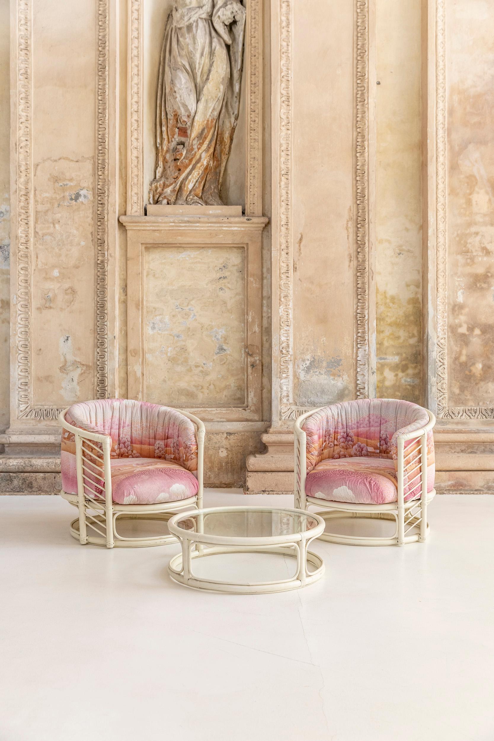 Italian white bamboo set composed by two round armchairs and a round shape coffe table with clear glass top. The armchairs have peculiar cushions in original fabric naif motif in pink and orange tones. 
Italy, 1970 circa.

Armchair measures: