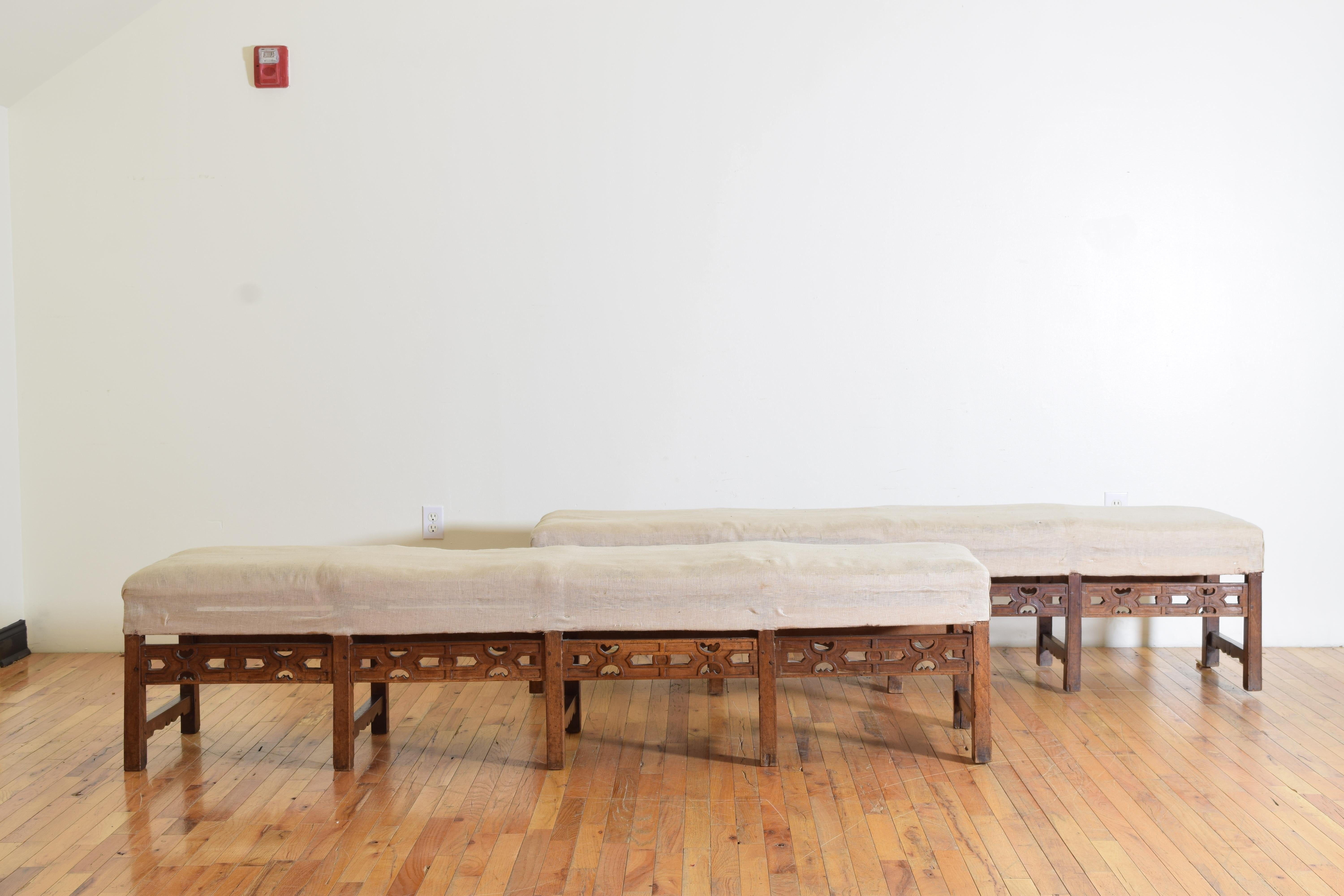 having fitted seats currently with a vintage muslin covering atop a frame consisting of block legs and a series of stretchers, the upper front stretchers with open carvings, the upper rear stretchers with more simple carvings, the lower stretchers