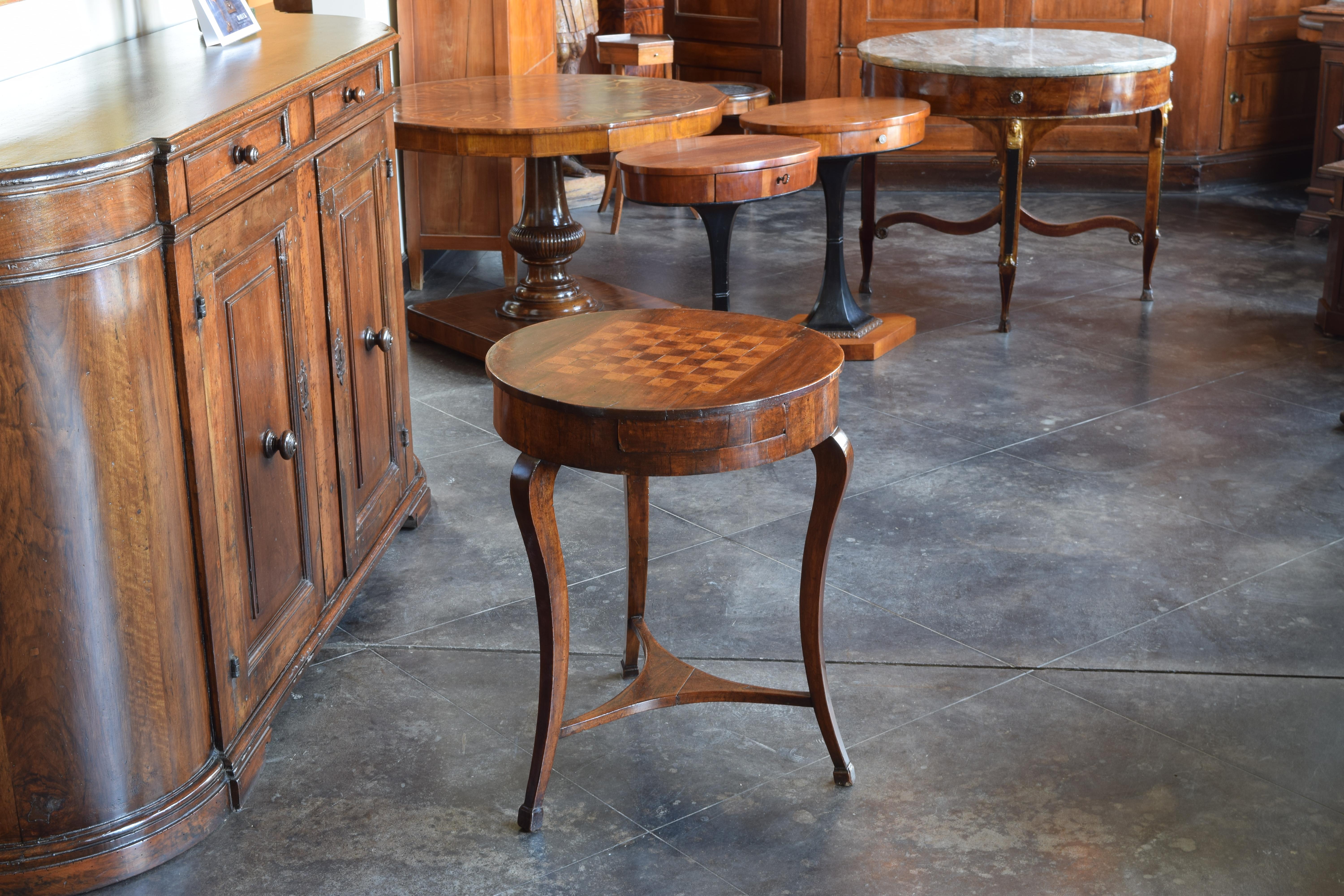 Made of solid walnut, the circular top with an inlaid game board, the case having three drawers and raised on curving legs joined by a shaped stretcher, the legs ending in block feet, second quarter of the 19th century.