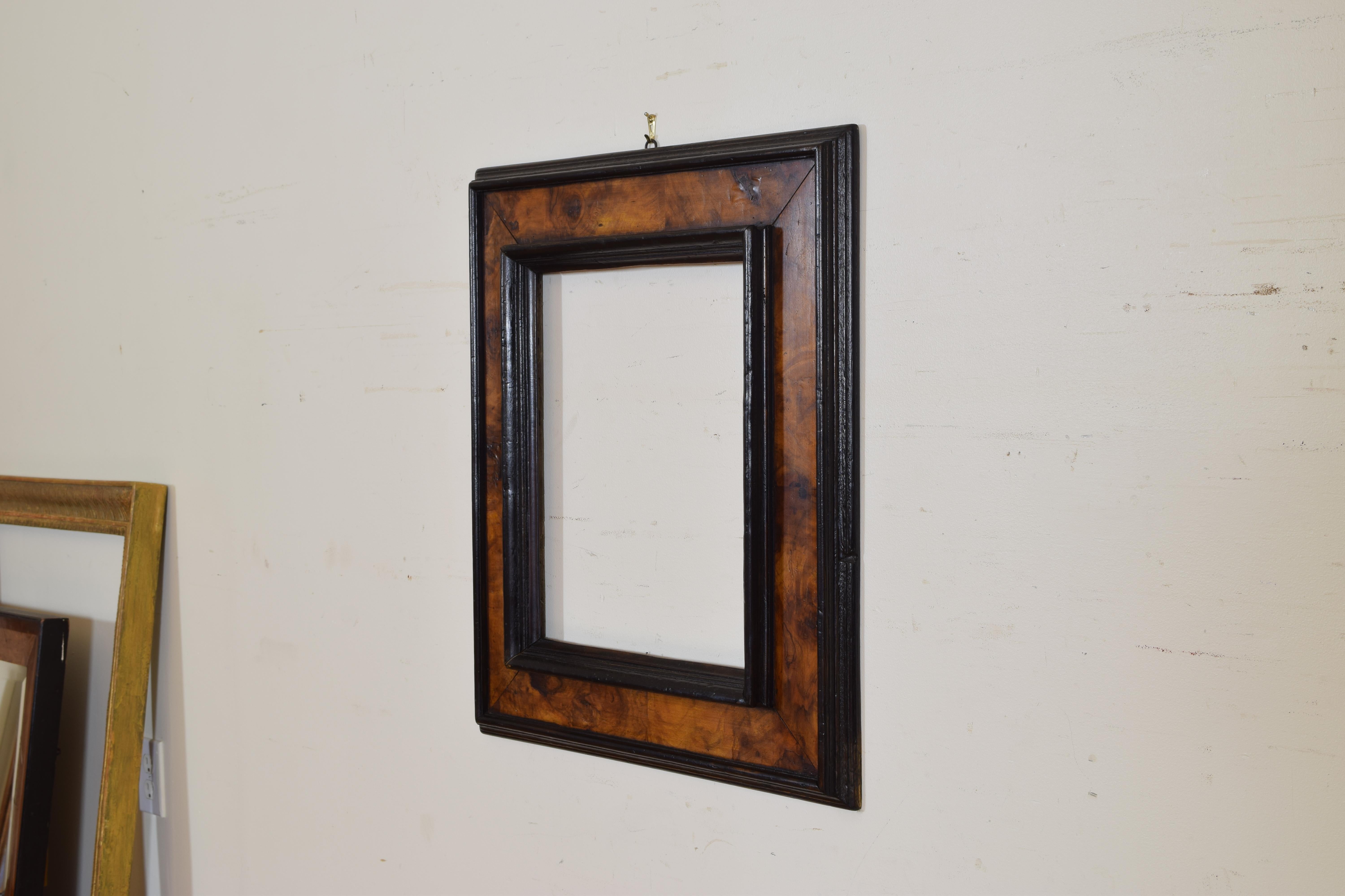 Having exterior and inner ebonized moldings, the surface veneered in olivewood.