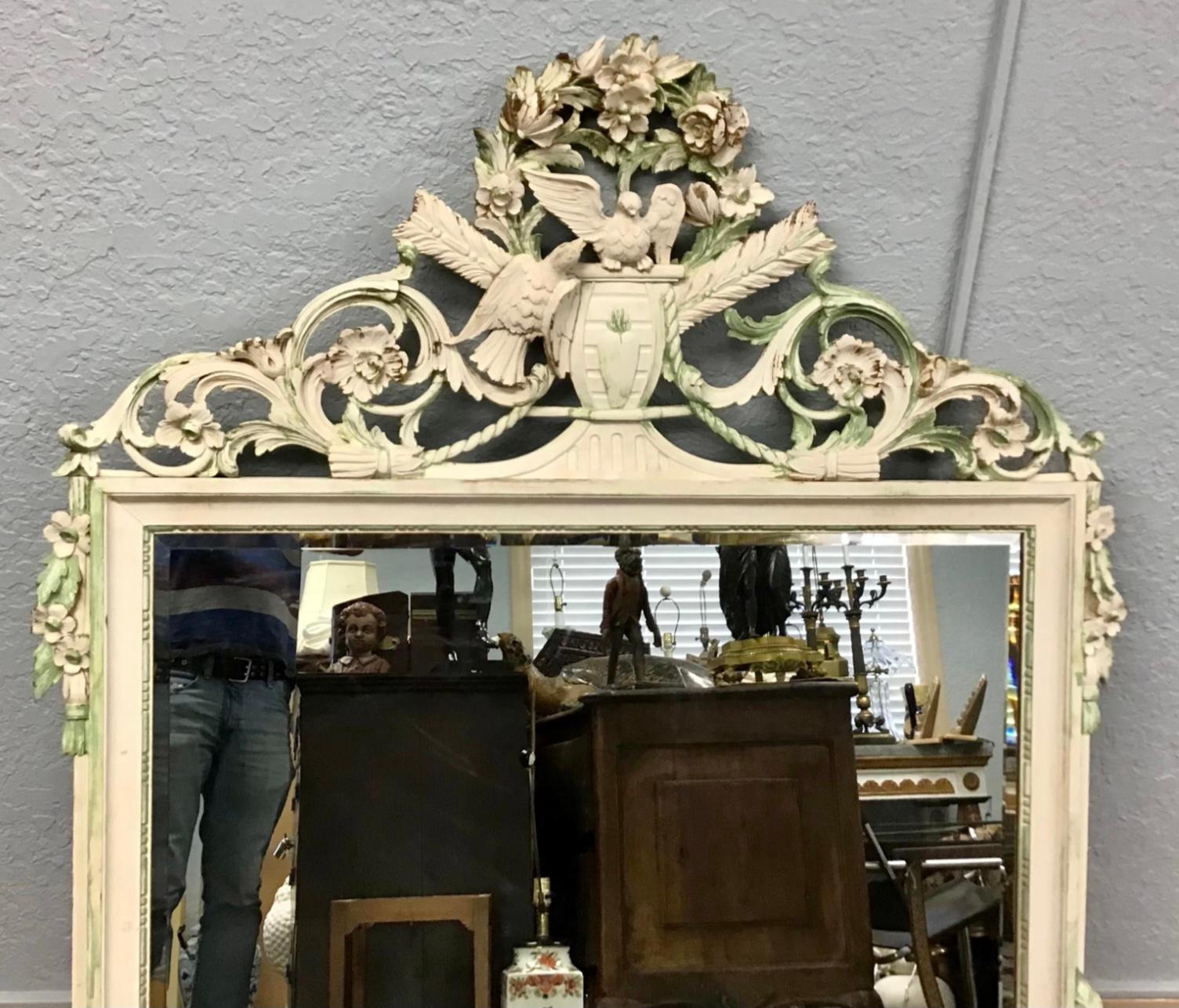 Italian, late 19th century. Cream and green painted carved wooden mirror in the neoclassical taste, having a foliate crest decorated with a pair of doves or lovebirds and arrows, the beaded inner fillet containing a beveled mirror plate. Wonderful