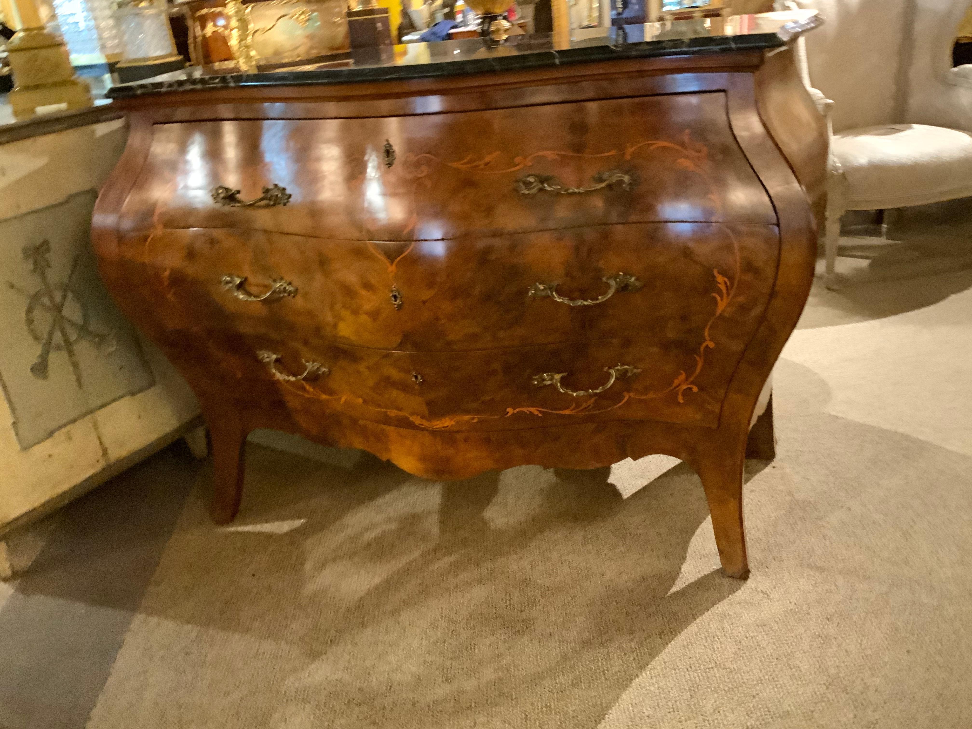 Burled wood in a soft warm hue makes this piece exceptional
The graceful curves of this bombe form add to the 
Beauty of this commode. Scroll work design in a marquetry 
Inlay further adds to the overall design of this commode.
A marble top that