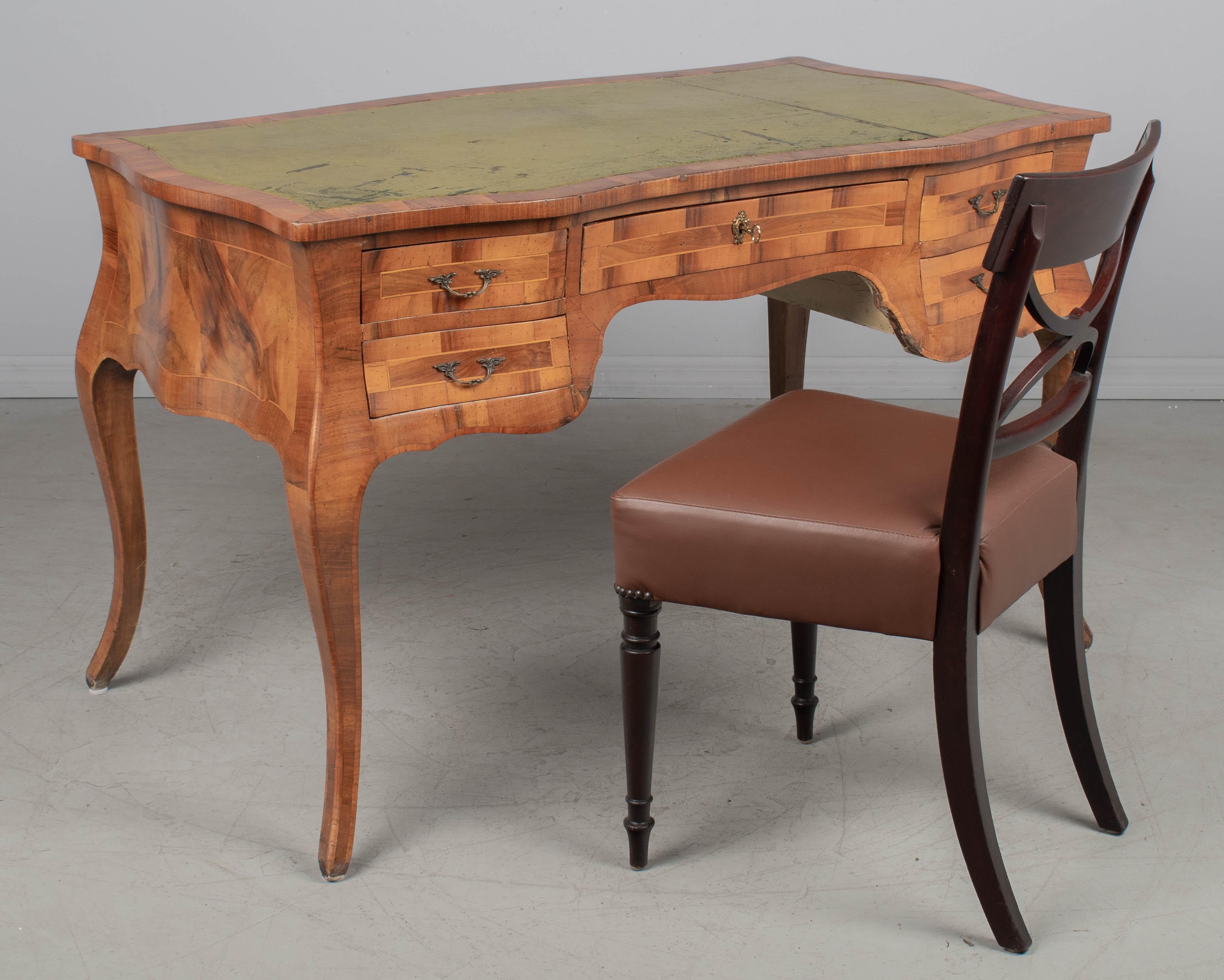 Ein italienischer Schreibtisch im Stil Louis XV aus Nussbaum und Olivenholz mit fünf Schubladen. Die Beschläge aus Messingguss sind nicht original, stammen aber aus dieser Zeit. Funktionierendes Schloss und Schlüssel. Originale grüne