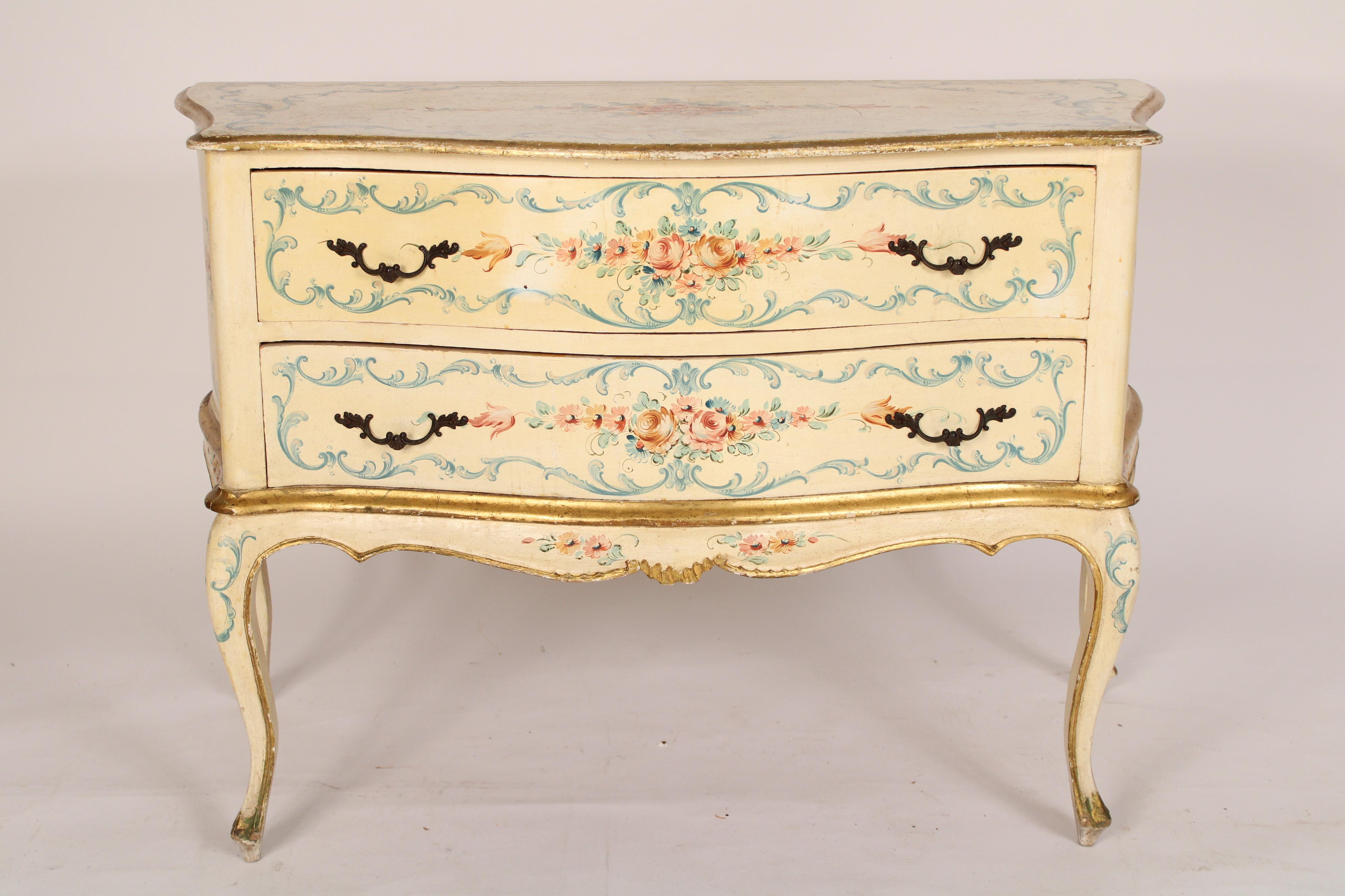 Italian Louis XV style painted and partial gilt chest of drawers, circa mid 20th century. The floral painted top with a serpentine front edge, thumb molded gilt decorated side and front edges, two floral painted serpentine shaped drawers with brass