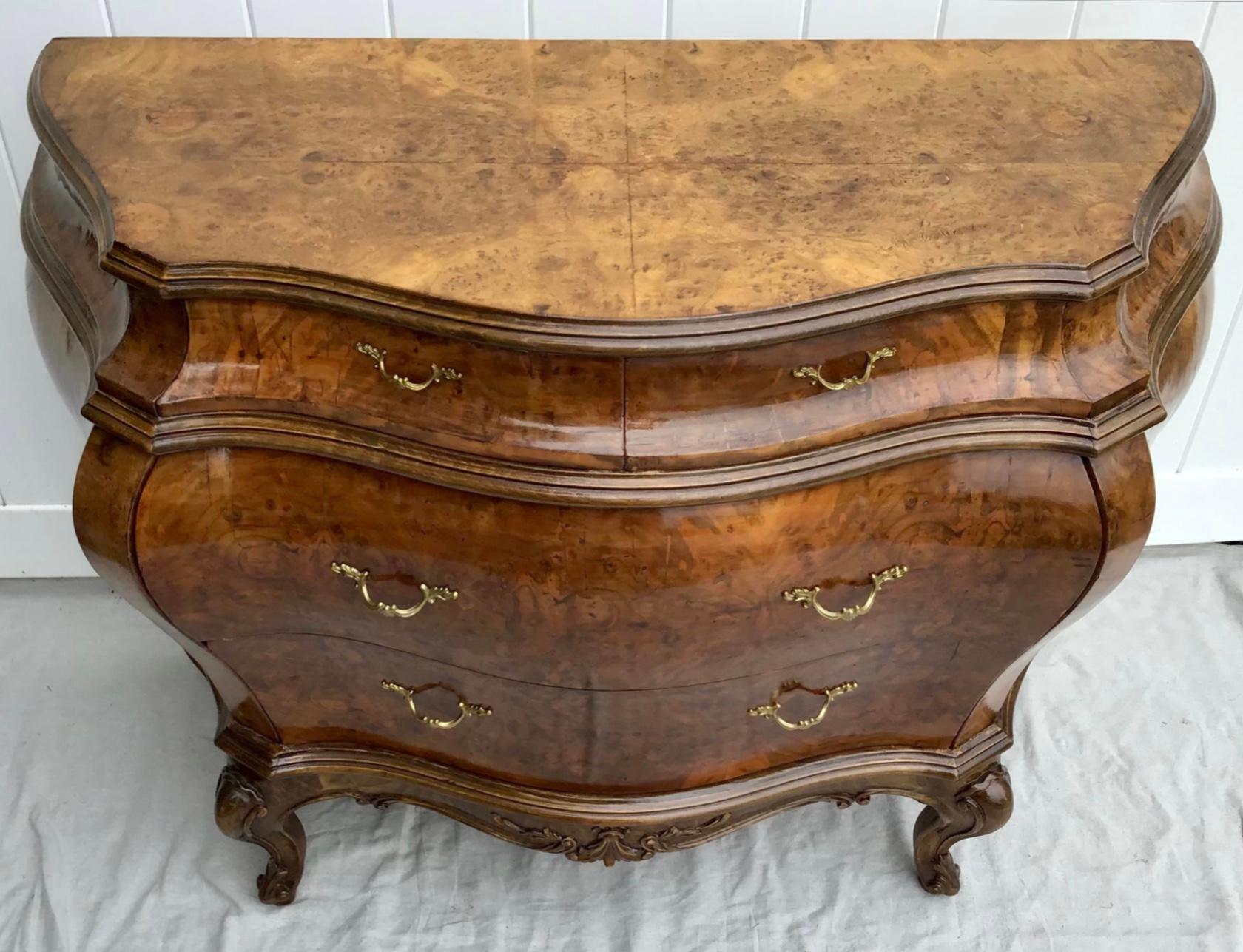 Italian Louis XV-style Bombay chest is made of wood covered in burl veneers in a beautiful golden stain finish. The chest features two small drawers above two large drawers with decorative brass drawer pulls and ample storage space. This Bombay