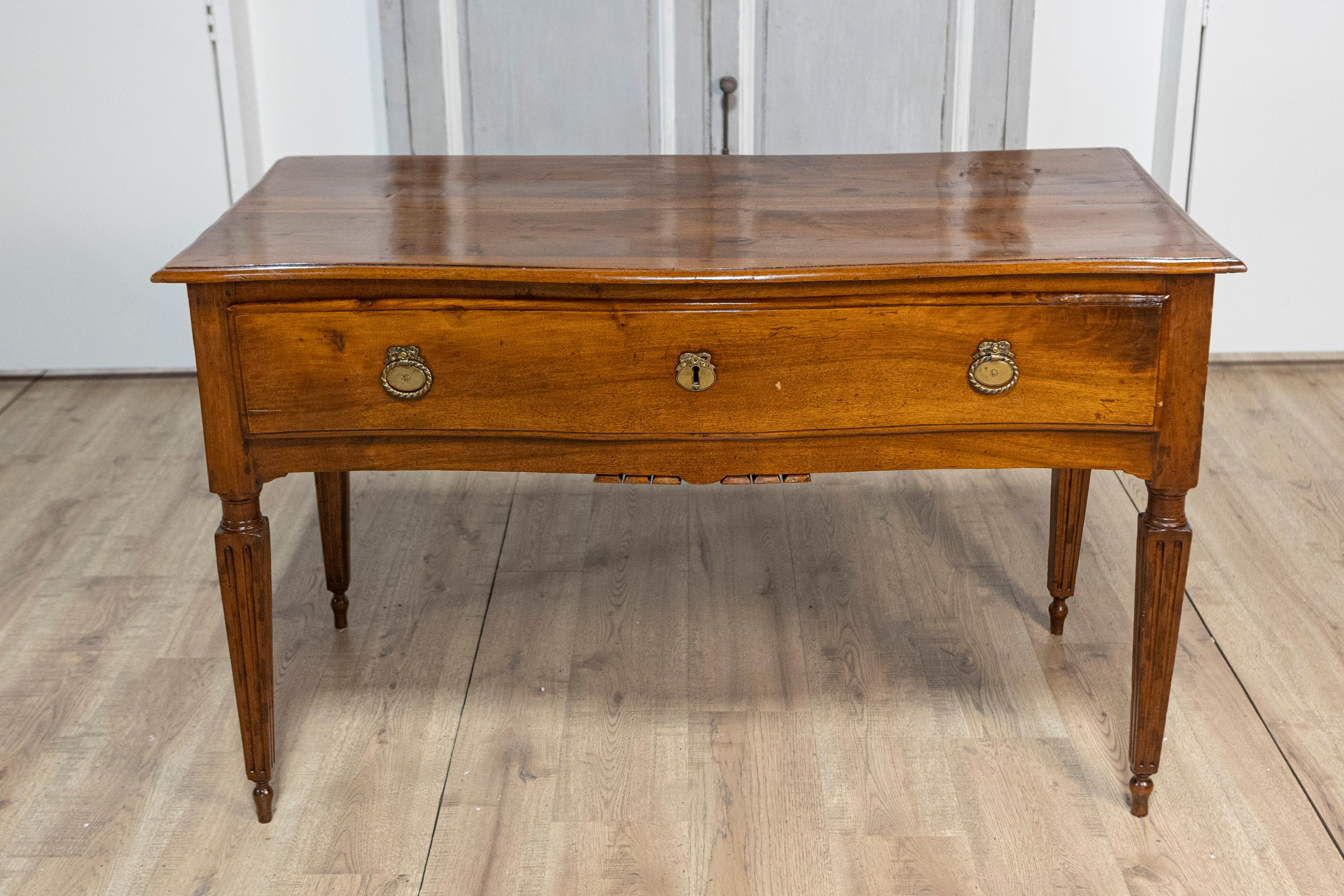 An Italian walnut console table from the 18th century with large drawer and tapered, fluted legs. This exquisite Italian walnut console table from the 18th century exudes timeless elegance and refined craftsmanship. The table features a large drawer