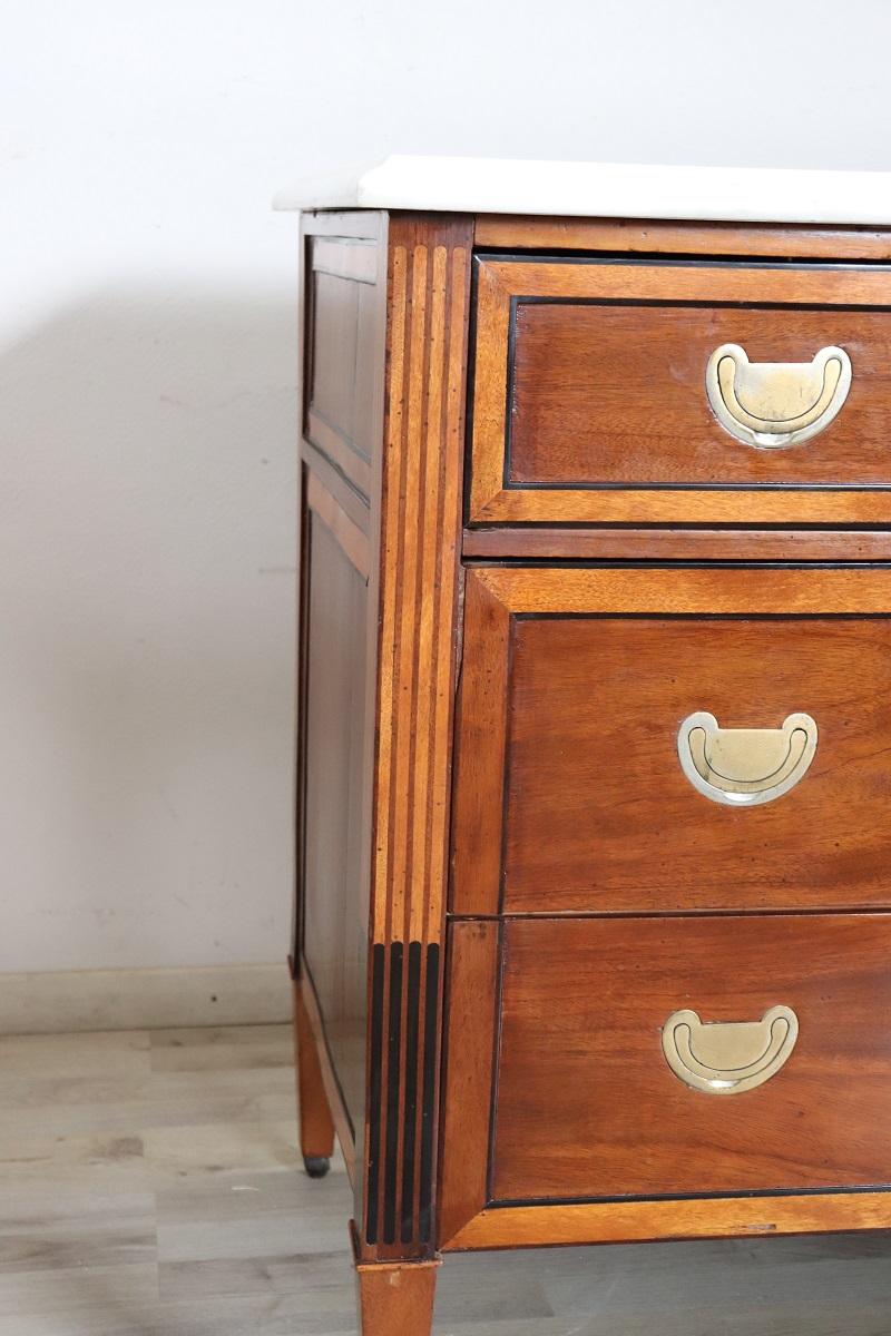 Ti presentiamo questa elegante cassettiera antica italiana risalente alla seconda metà del XVIII secolo, il periodo Luigi XVI. Un arredamento estremamente raffinato.

Realizzata in noce pregiato con una tonalità chiara, la sua linearità riflette