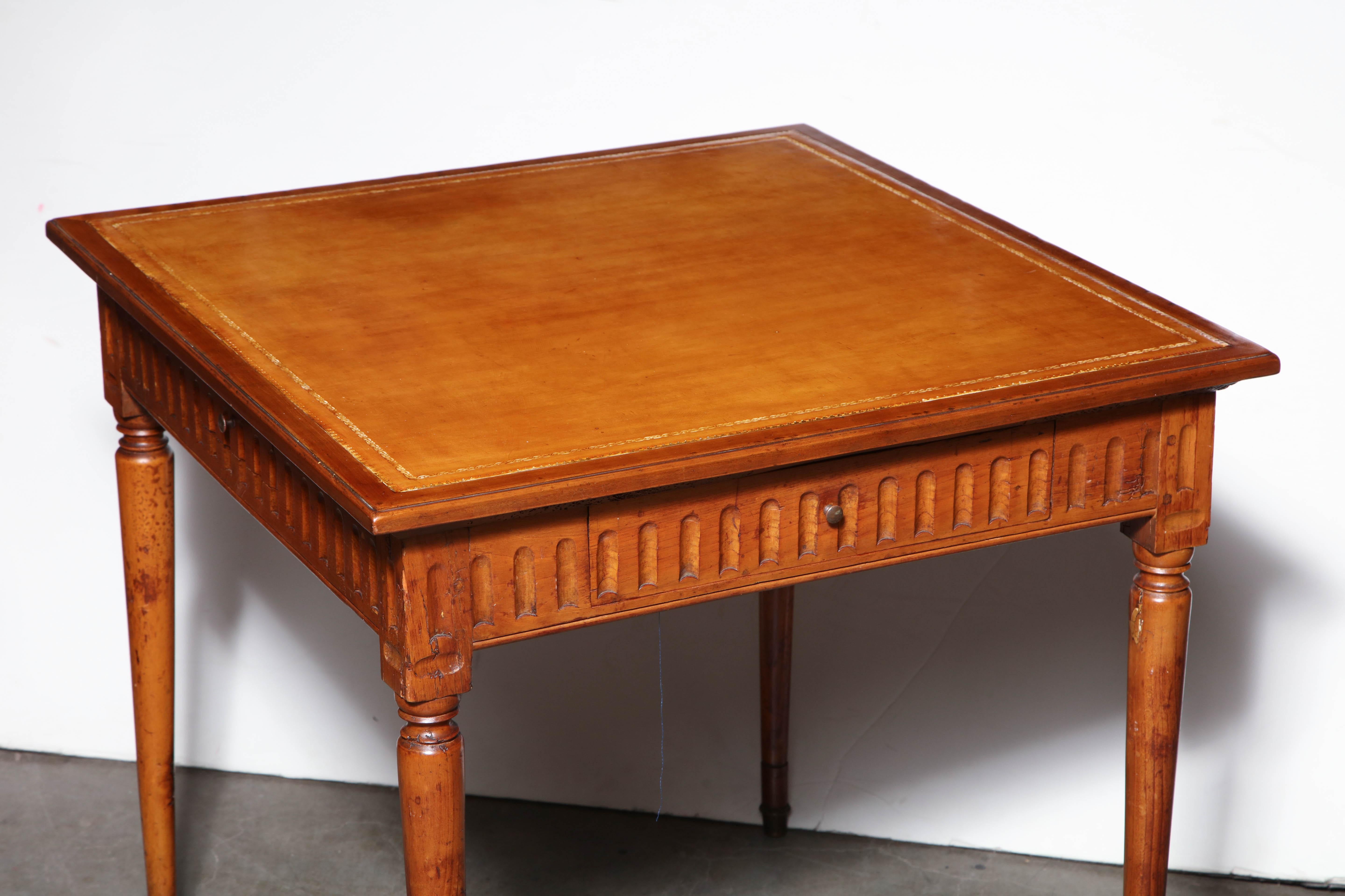Italian walnut Louis XVI square game table with gold tooled leather top, fluted apron, three drawers and turned and tapered legs.