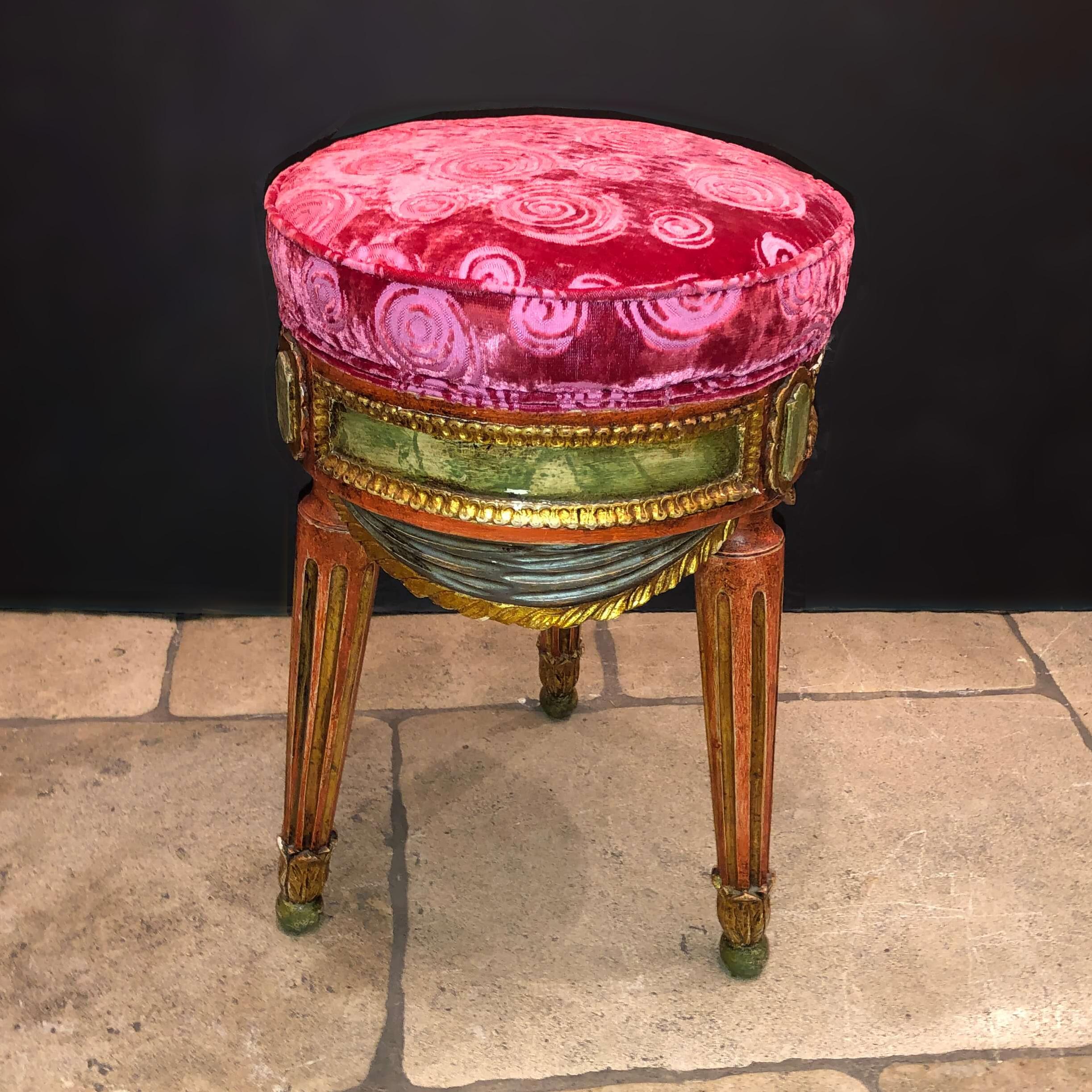 An Italian hand painted round Louis XVI style Tabouret stool, with a velvet upholstered boxed cushion seat, gilt trim, carved drapery on out-flaring turned, tapered and fluted legs, late 19th century.