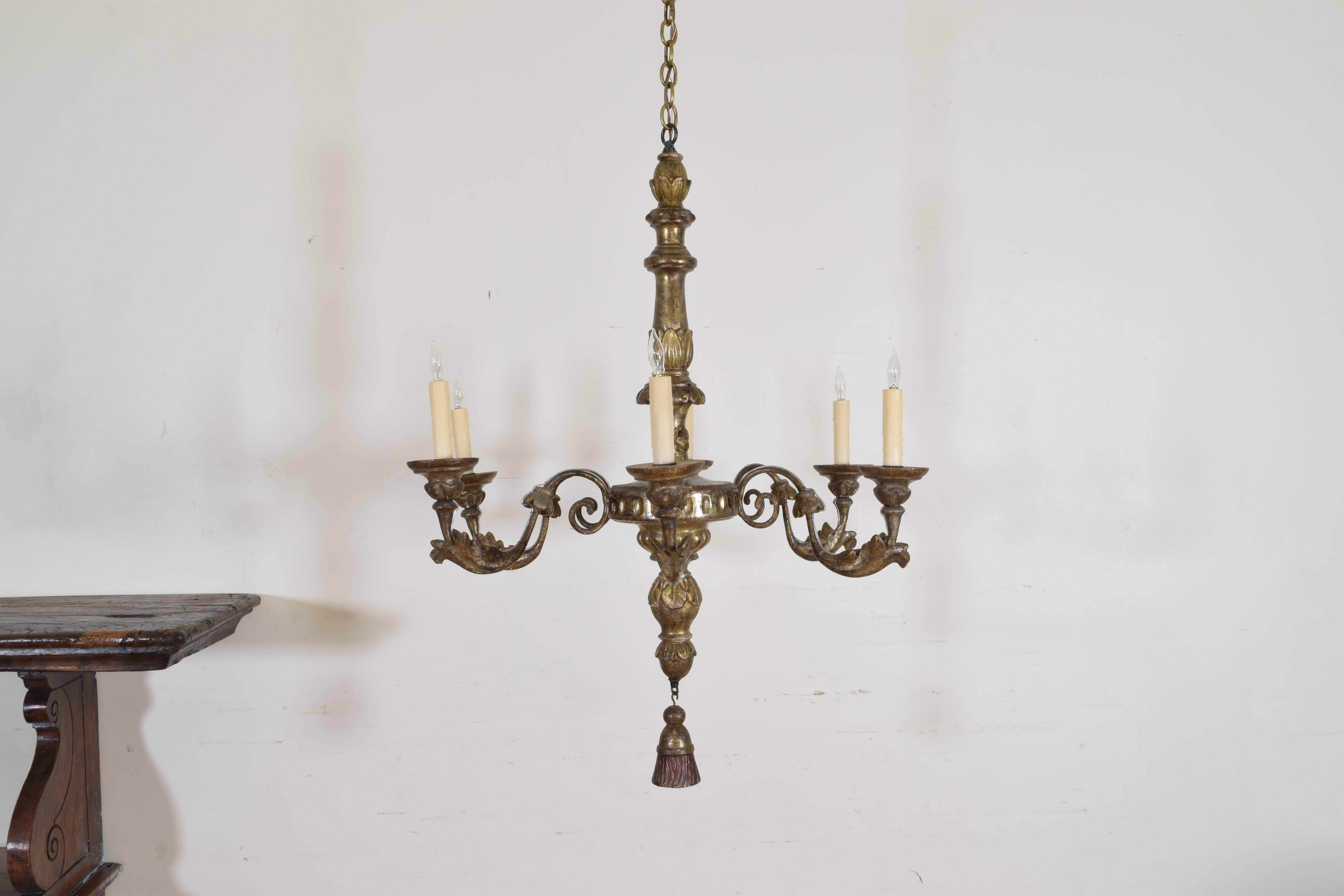 The carvings of foliate and neoclassical forms, the standard issuing six arms each with downward bell flowers and foliate scrolls, with a wooden tassel terminal below, now drilled and wired for electricity.