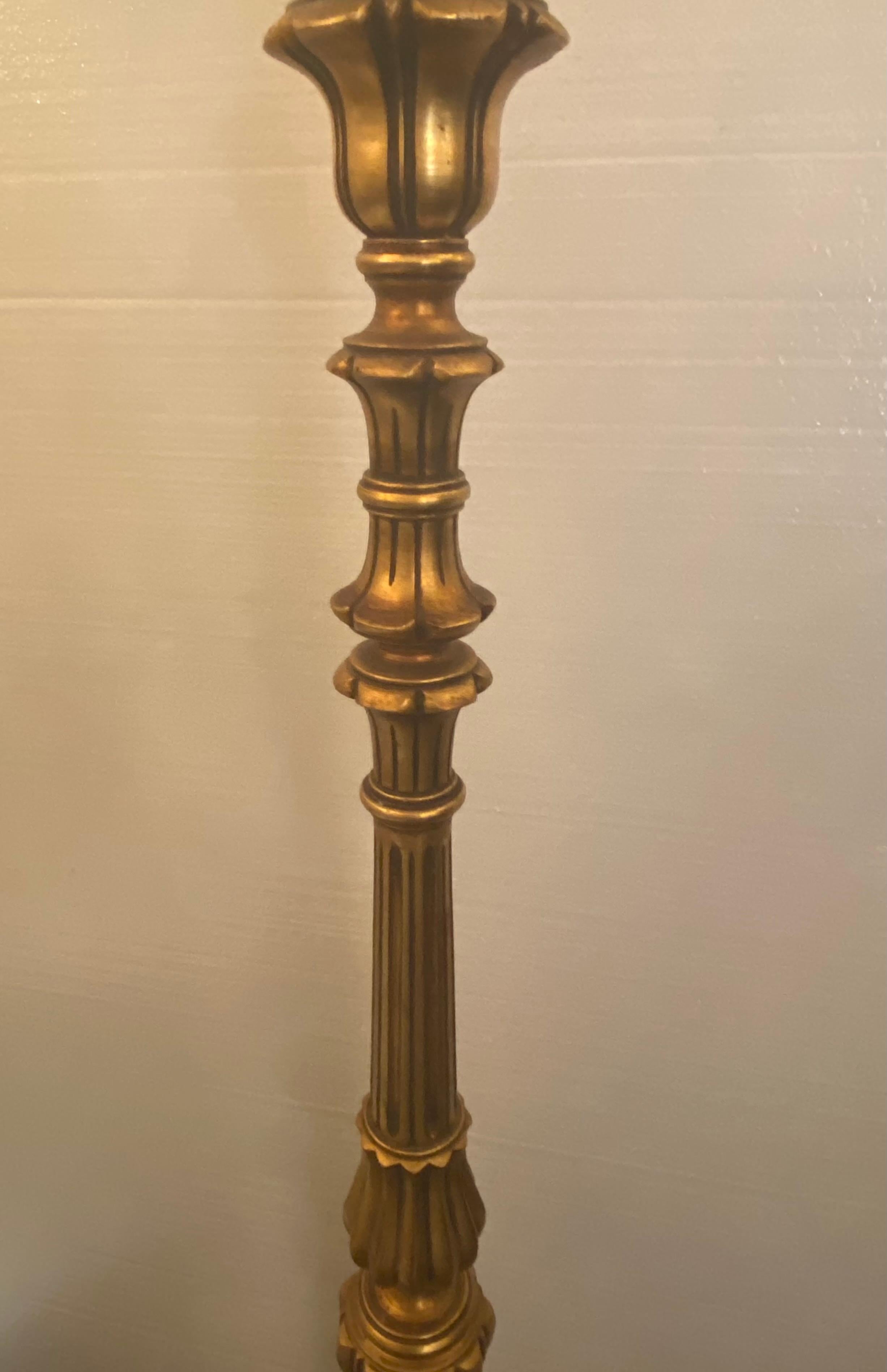Italian Louis XVI style giltwood standing lamp, 20th c., fluted and turned standard ending in single large faux candle fitted with three light fixtures, rising on round gadrooned base.