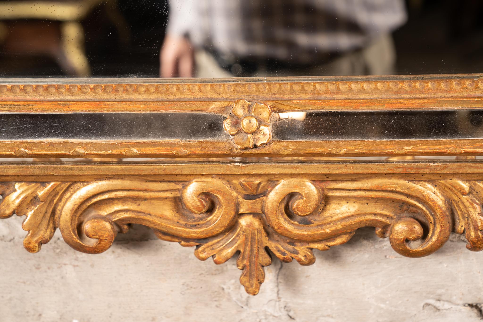 Ce miroir italien de style Louis XVI présente des feuilles d'or véritables et date du milieu des années 1900. La pièce est sculptée à la main avec des détails magnifiques. Notez les boiseries qui partent des coins, la guirlande en haut et les