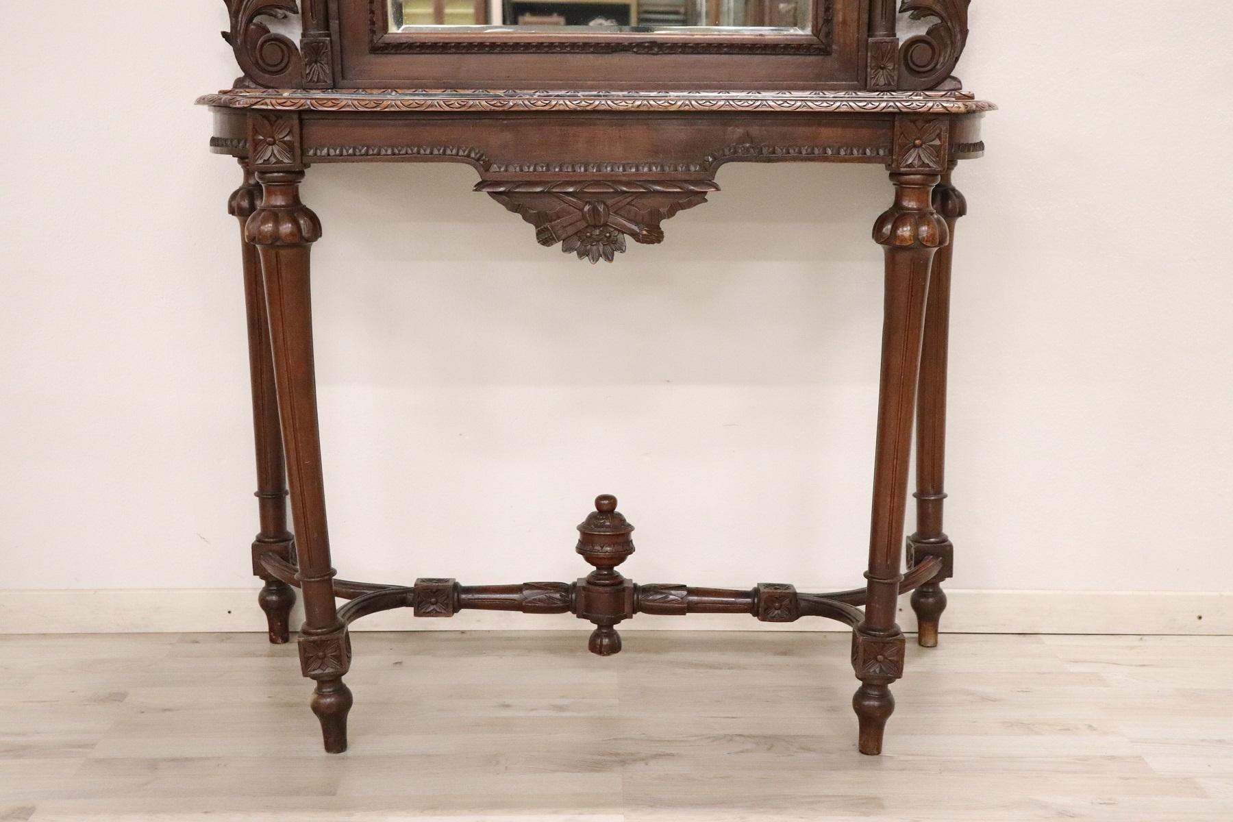 Italian antique console table, 1920 in Louis XVI Style. Characterized by precious walnut with wood carving. Refined carving work performed by an important cabinet maker look at the bow made high above the mirror. Look at the front legs moved
