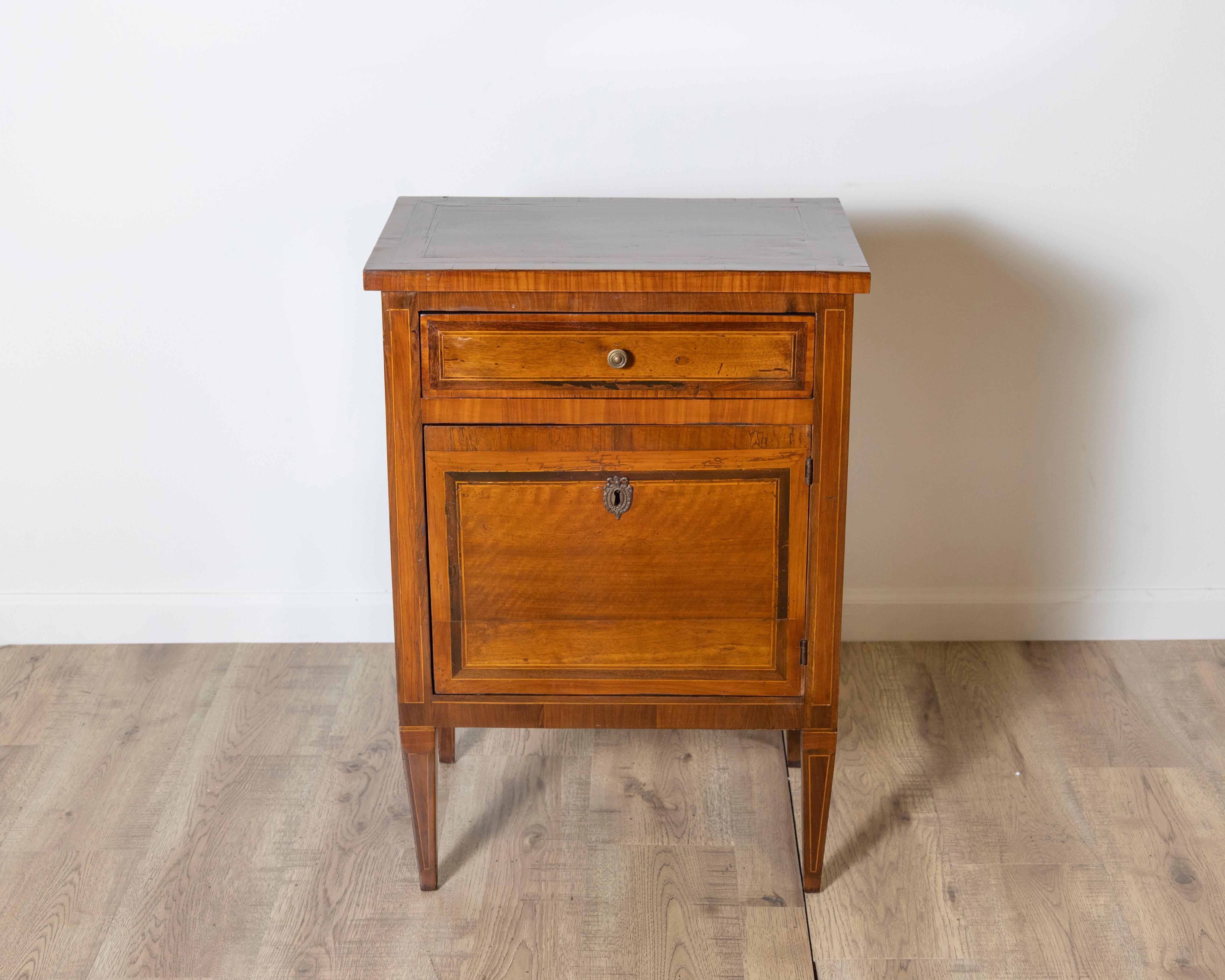 Dieser raffinierte italienische Louis-XVI-Nachttisch aus dem späten 18. Jahrhundert verkörpert die neoklassischen Ideale von Symmetrie, Proportion und schlichter Eleganz. Der aus massivem Nussbaumholz gefertigte und mit zarten Fruchtholzintarsien