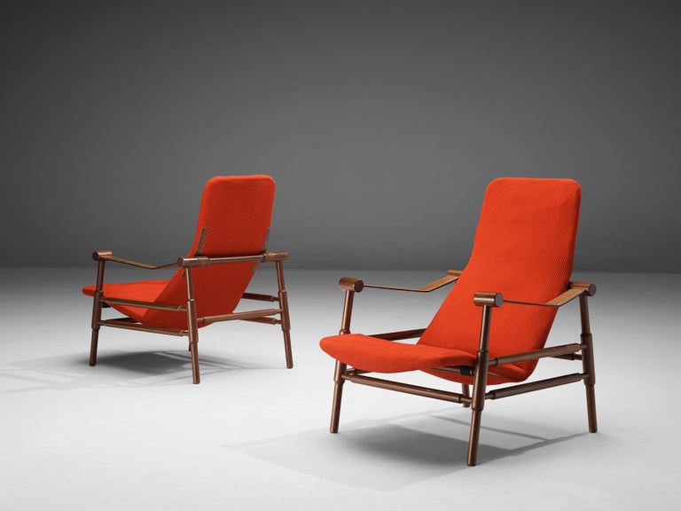 Lounge chairs, teak, fabric, leather, Italy, 1960s. 

Pair of lounge chairs executed in teak and orange fabric. Its overal appearance remind of an enlarged safari chair model. 
These chairs feature a wonderfully carved teak frame. On the upper