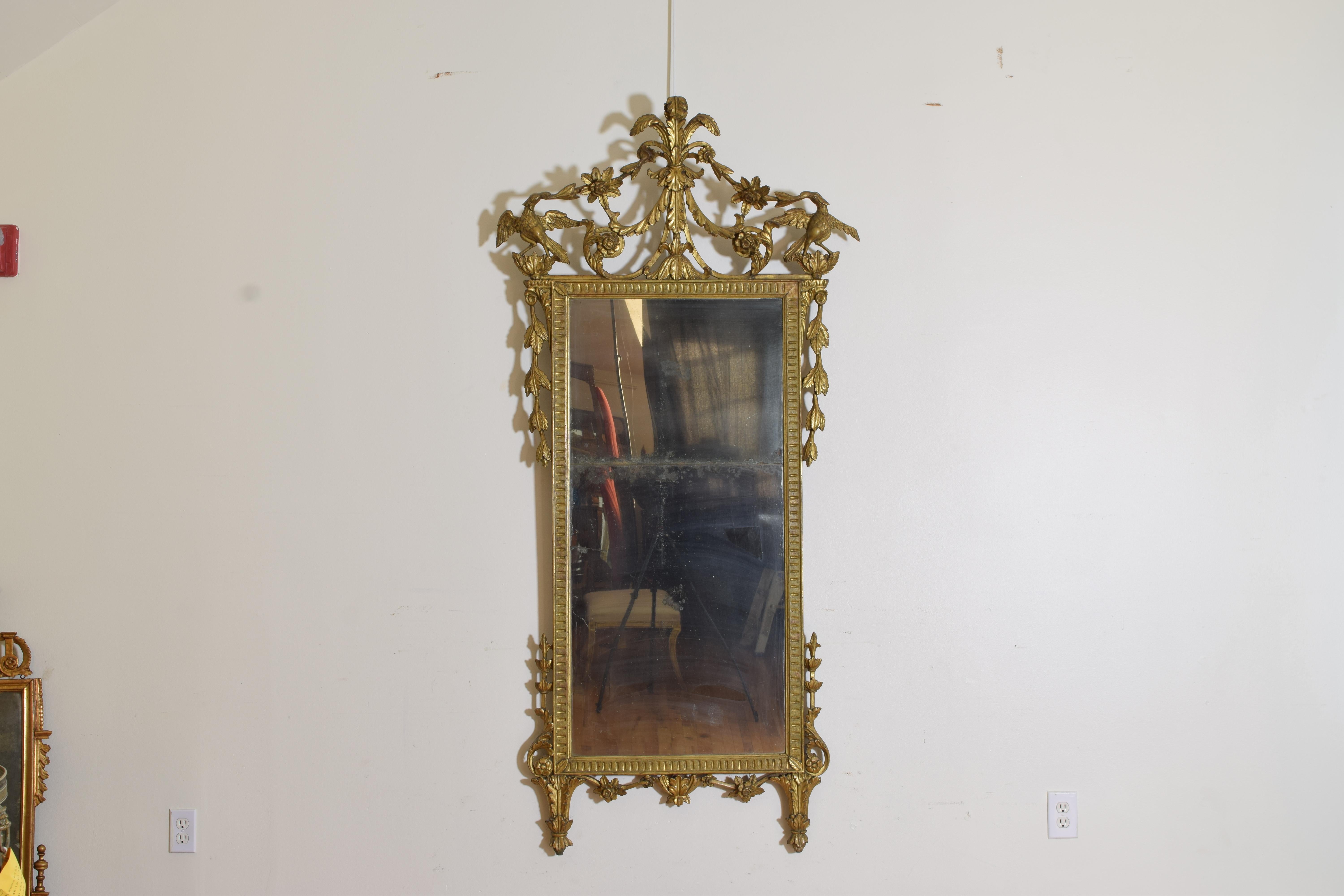 Having an interior rectangular frame with a furrowed molded edge and an original two-piece mirrorplate, the inner frame surmounted by a Prince of Wales finial and leaf-form swags, floral sprays, and rosettes, with carved birds at the upper corners,