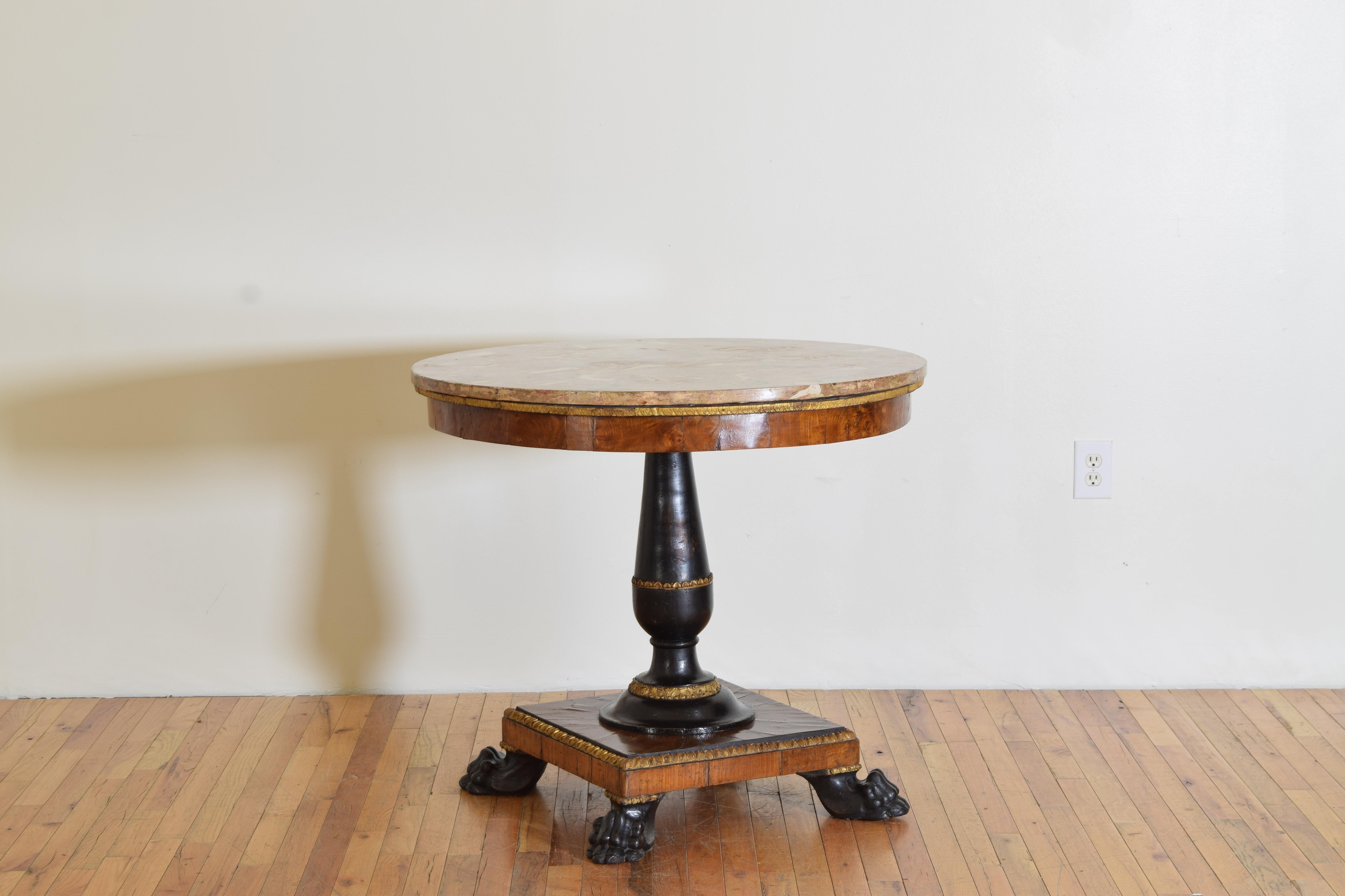 Having a circular hand painted scagliola top resting atop a circular frame, the thick walnut veneer of a pronounced grain, the ebonized columnar standard with carved giltwood rings resting upon a walnut veneered square veneered and giltwood trimmed