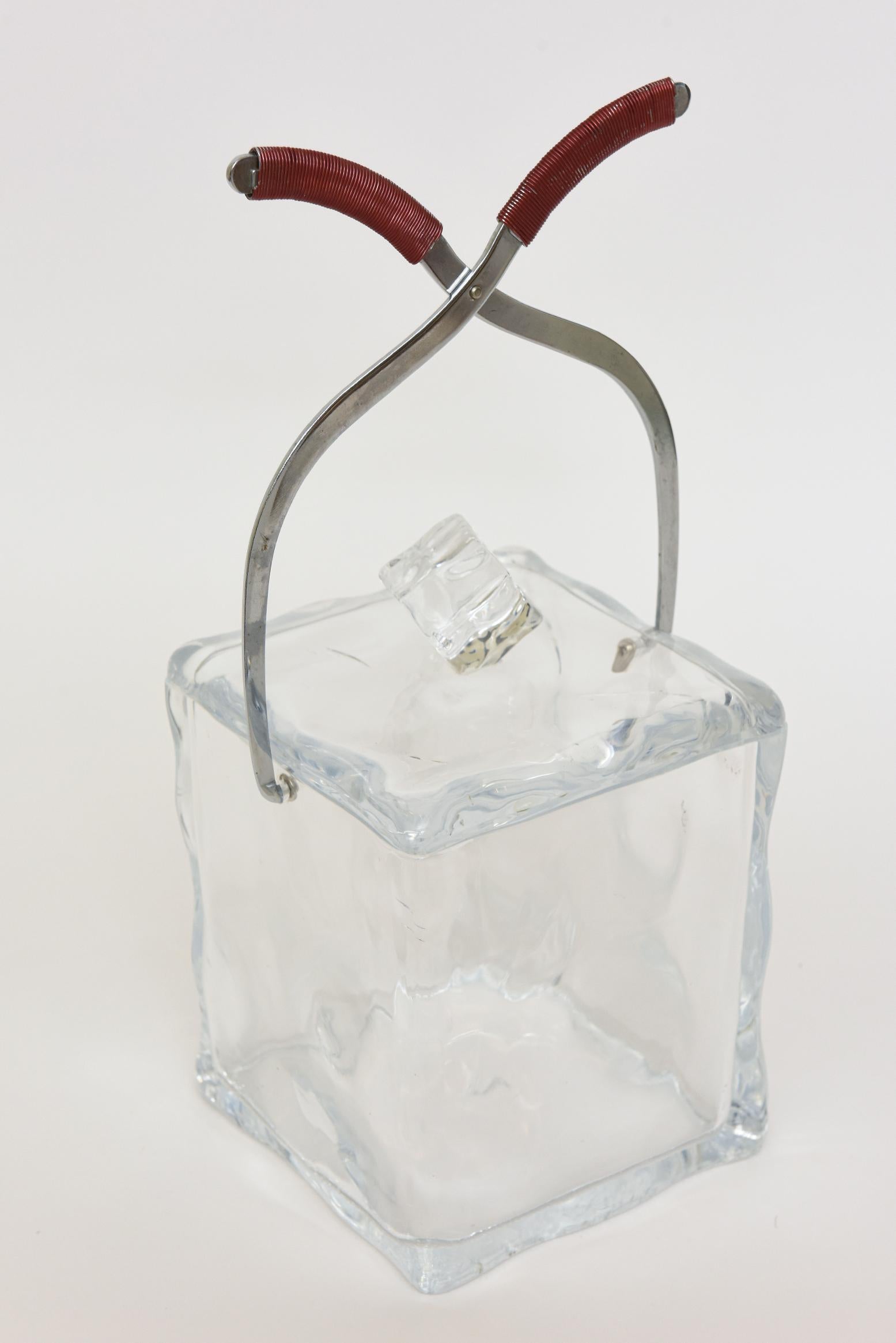This Italian fun vintage square clear lucite ice bucket has the chrome plated twisted tongs that act as the handles with wrapped red wire at the top. The tongs fold down. From the late 60's. To the top is an ice cube that is set off center on an