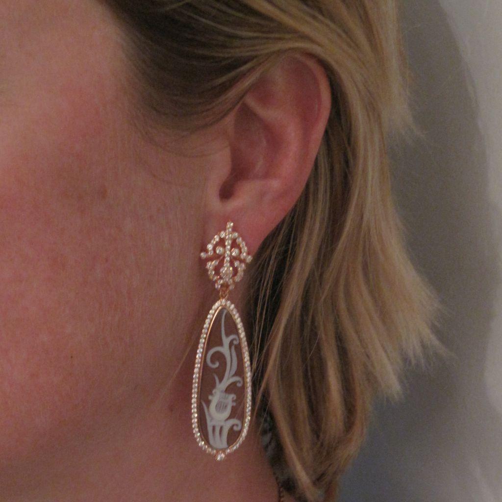 Earrings in vermeil, silver covered with rose gold.
Each cameo earring is composed of openwork arabesques entirely set with small crystals that hold a drop-shaped cameo on shell , depicting a vegetal decoration and a lyre, closed- set and edged all