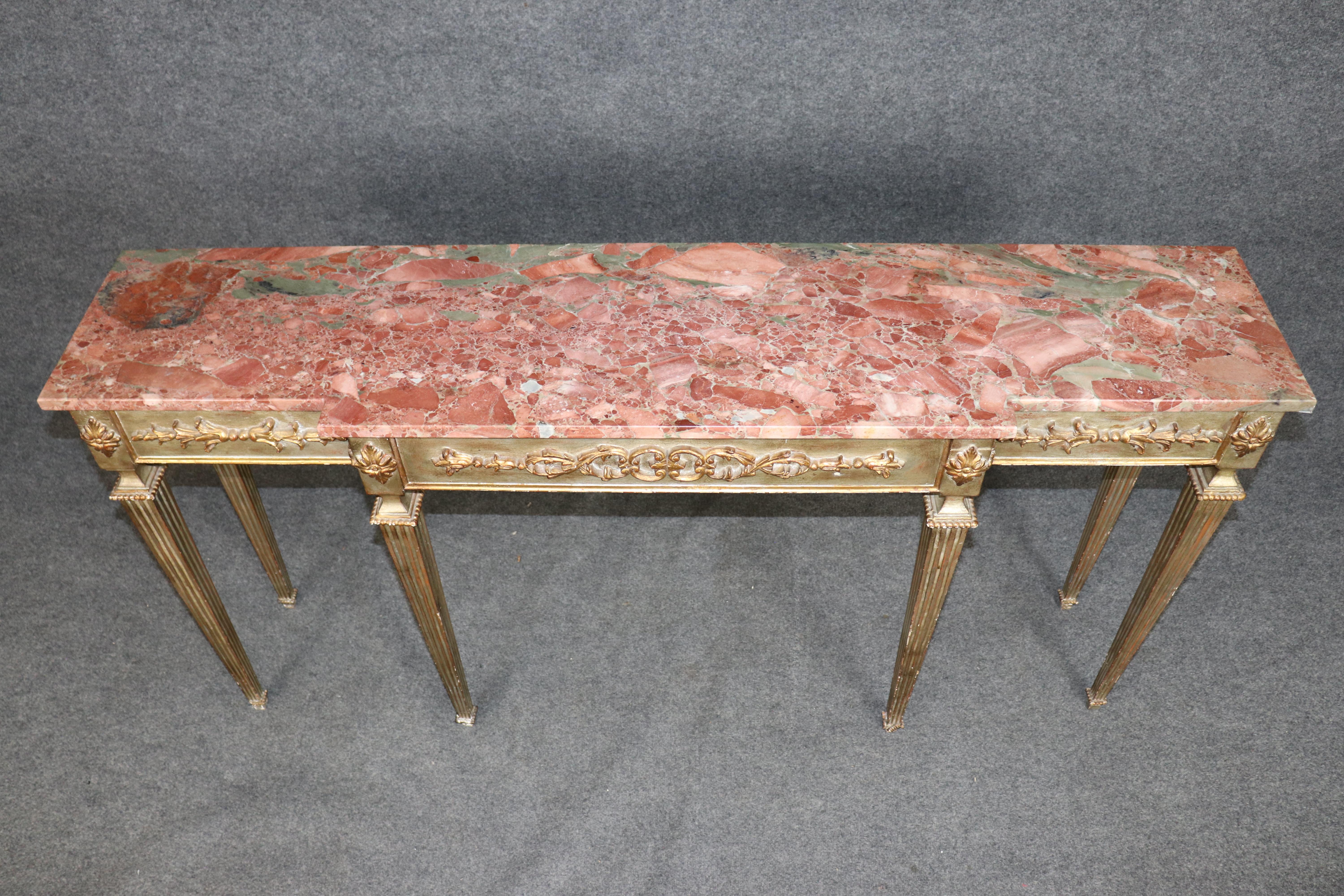 This exquisite Italian Louis XVI style console table showcases timeless neoclassical elegance with a refined combination of silver and gold leaf accents and a richly veined marble top. The rectangular top features warm tones of rose and cream