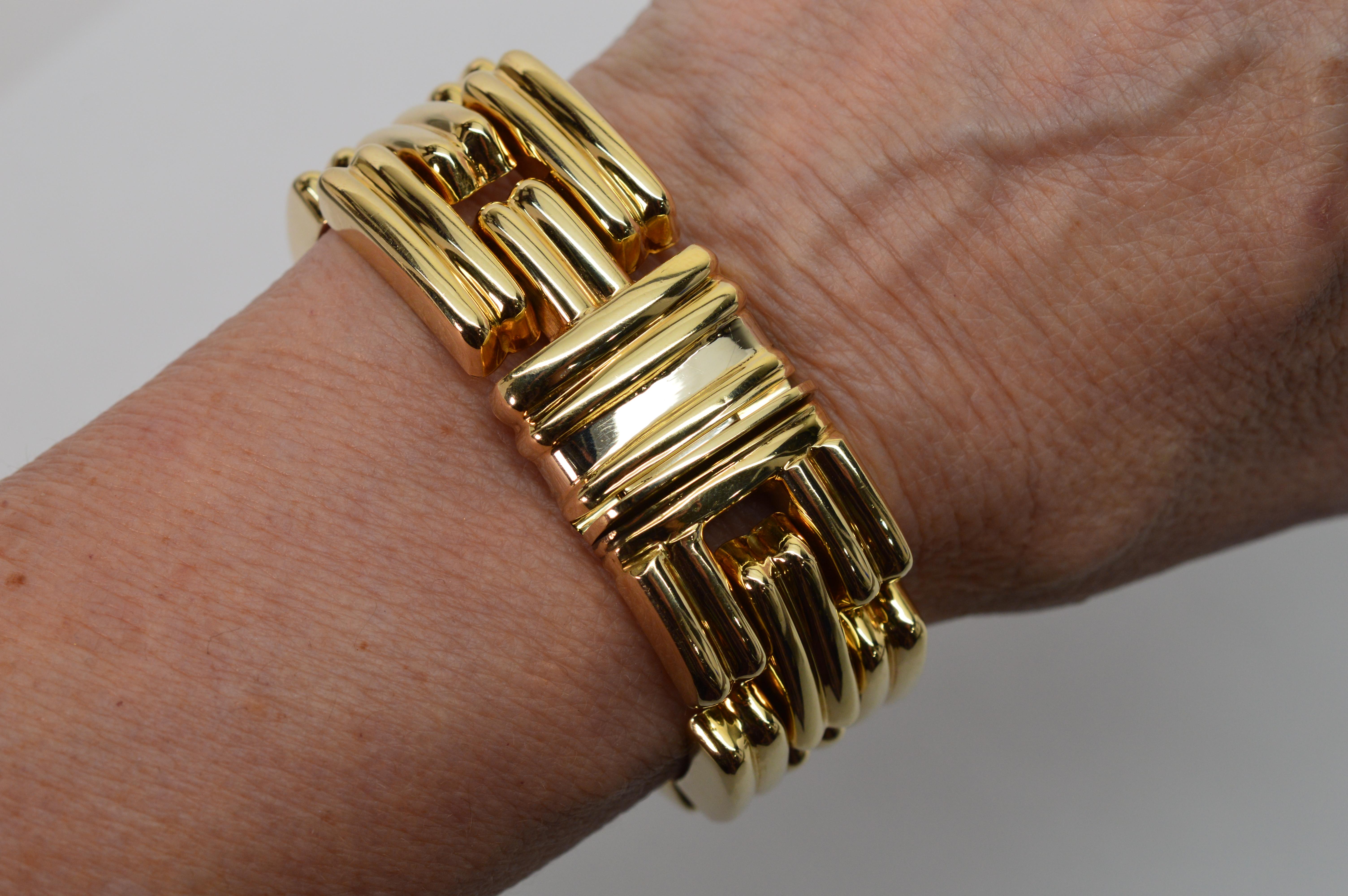 Superb Italian craftsmanship is evident in this highly polished fourteen karat 14K yellow gold Retro bracelet. Three rows of individually hinged stylized links give this bold statement bracelet its fluid movement. The buckle inspired detail can be