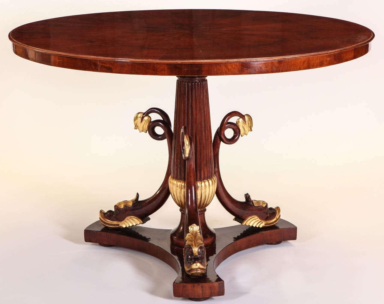 Une élégante  Table centrale italienne en acajou et parchemin doré avec un plateau circulaire au-dessus  un support de balauster centré avec  un triple dauphin addortif sur une base triforme.  
Décoration intemporelle pour votre intérieur. 
Très bon