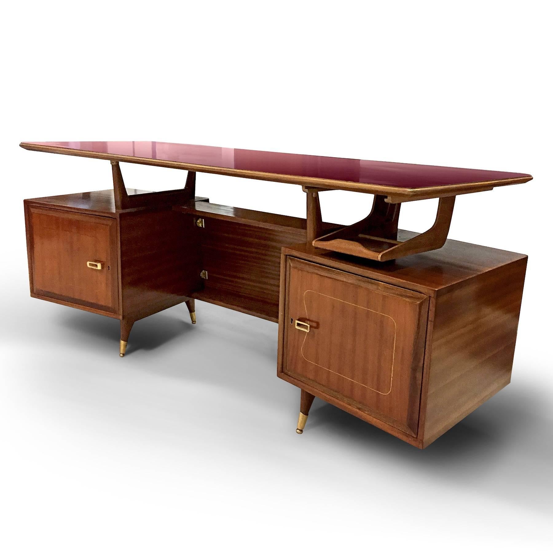 Unique design for this Italian executive desk of 1950s, attributed to La Permanente Mobili Cantù.
The structure is in mahogany veneer, finished with brass details.
Two doors open to reveal three amazing bent plywood drawers on either side.
It’s