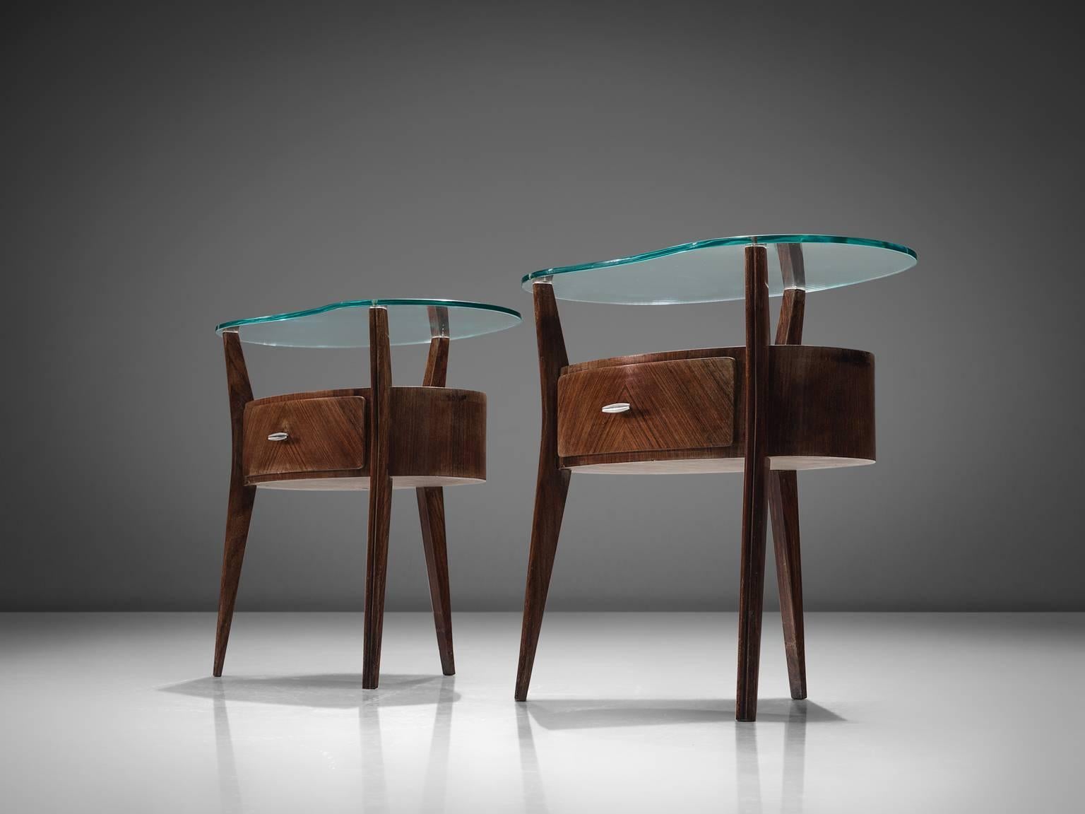 Nightstands, mahogany, glass and metal, Italy, 1950s.

These two side tables or nightstands are refined and soft-edged. The cabinets feature three legs and the main body features a drawer. The free-formed glass top rests on the three legs that
