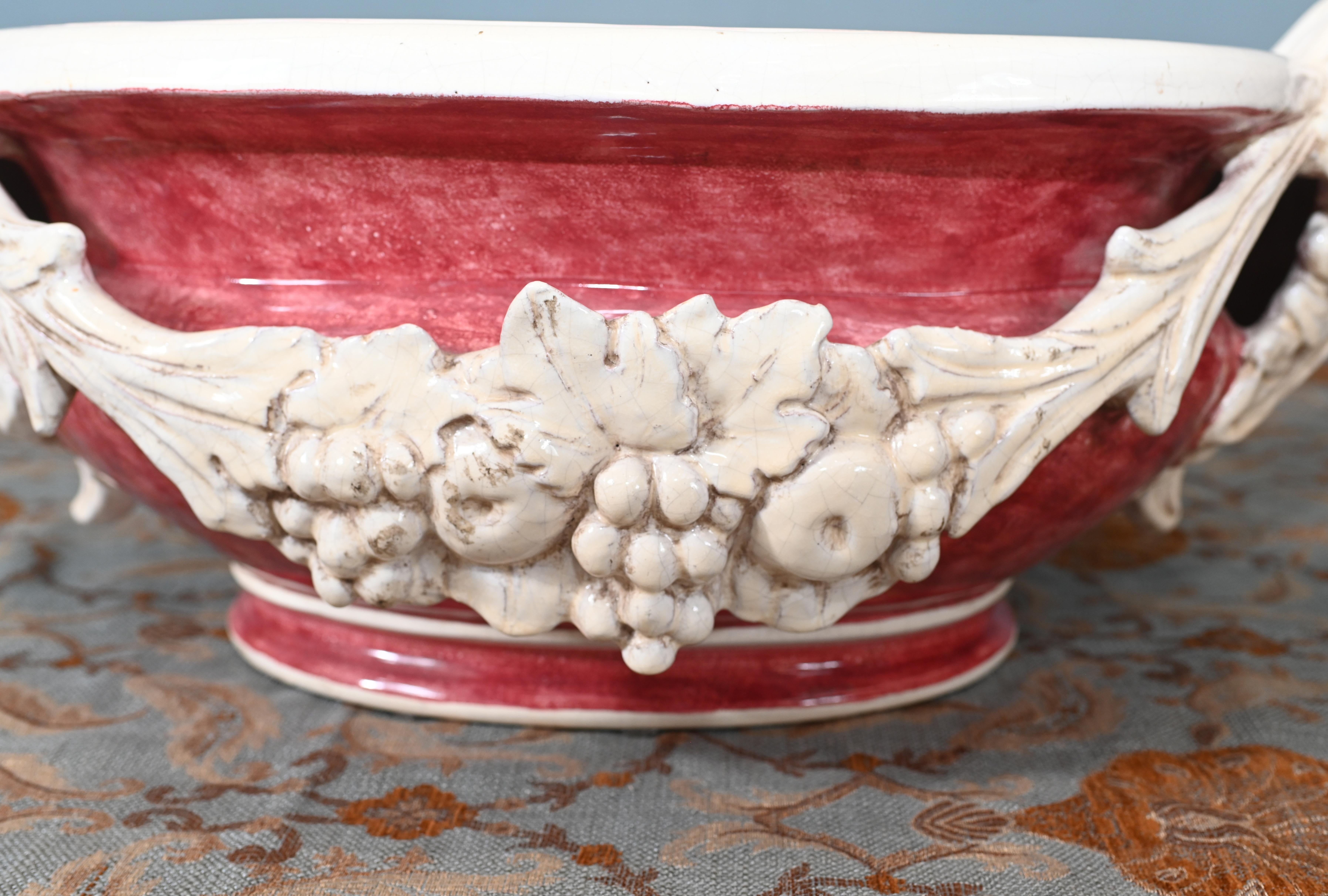 Sie sehen eine wunderschöne italienische Majolika-Porzellan-Jardiniere oder Pflanzgefäß
Aufwendig verziert mit einer Traubenschärpe, die durch das Rosa der Hauptschale abgesetzt ist
Äußerst dekoratives Mittelstück, das mit Obst und Blumen toll