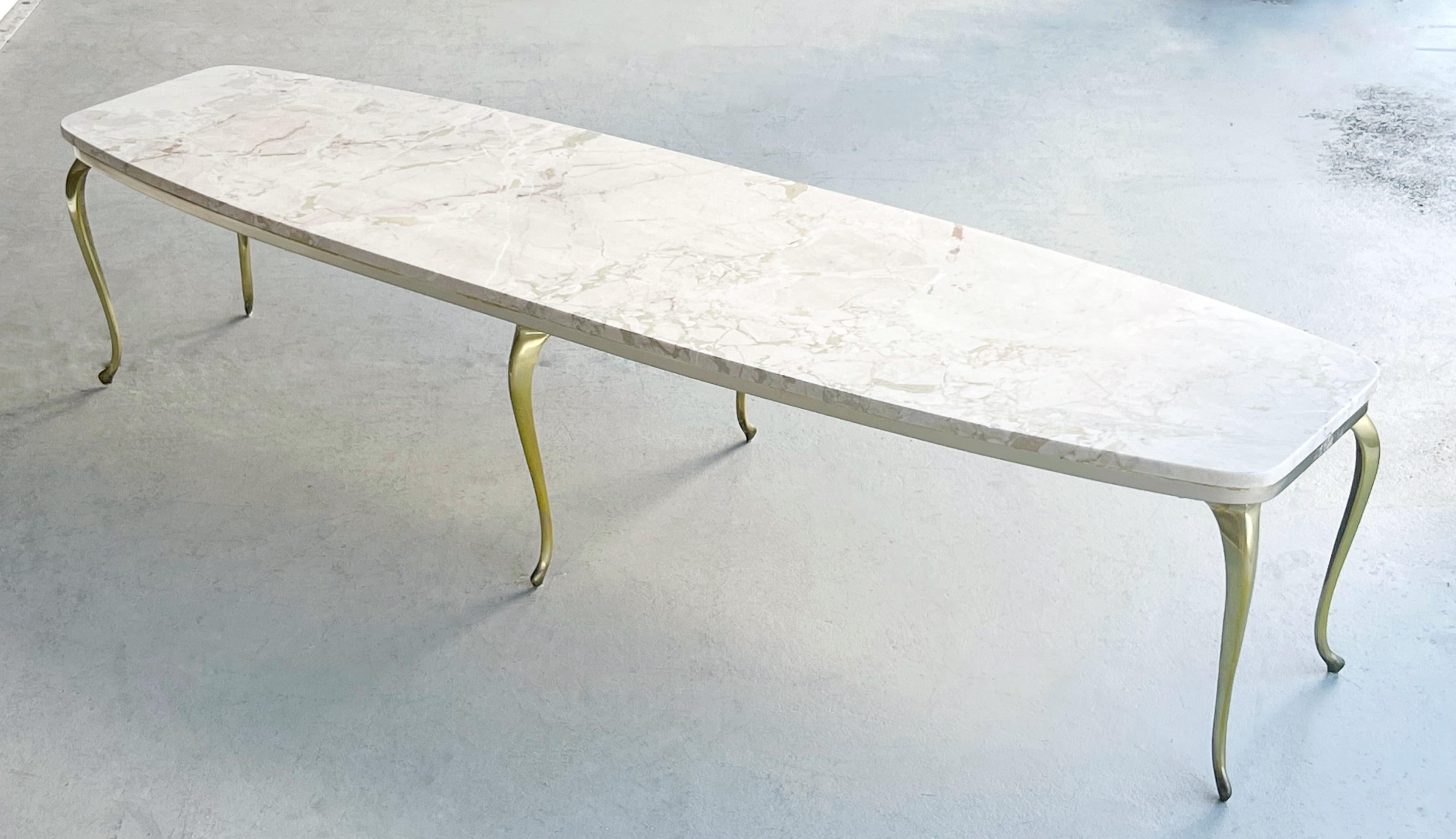 An Italian marble and brass 72” long coffee table. The marble top seats on a wood wood base with 6 graceful slender brass legs. 