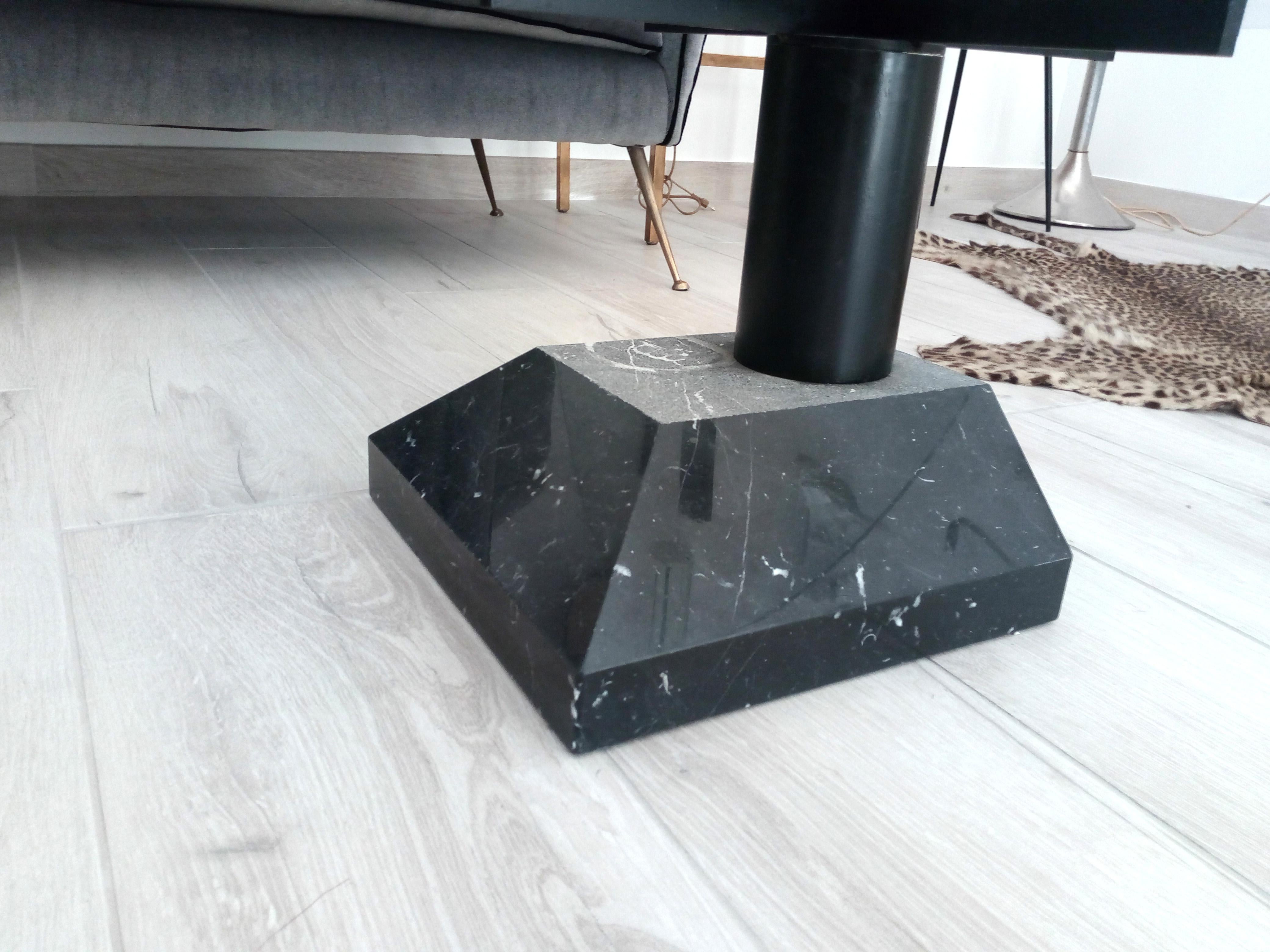 Particular coffee table with black marble base and circular glass top.