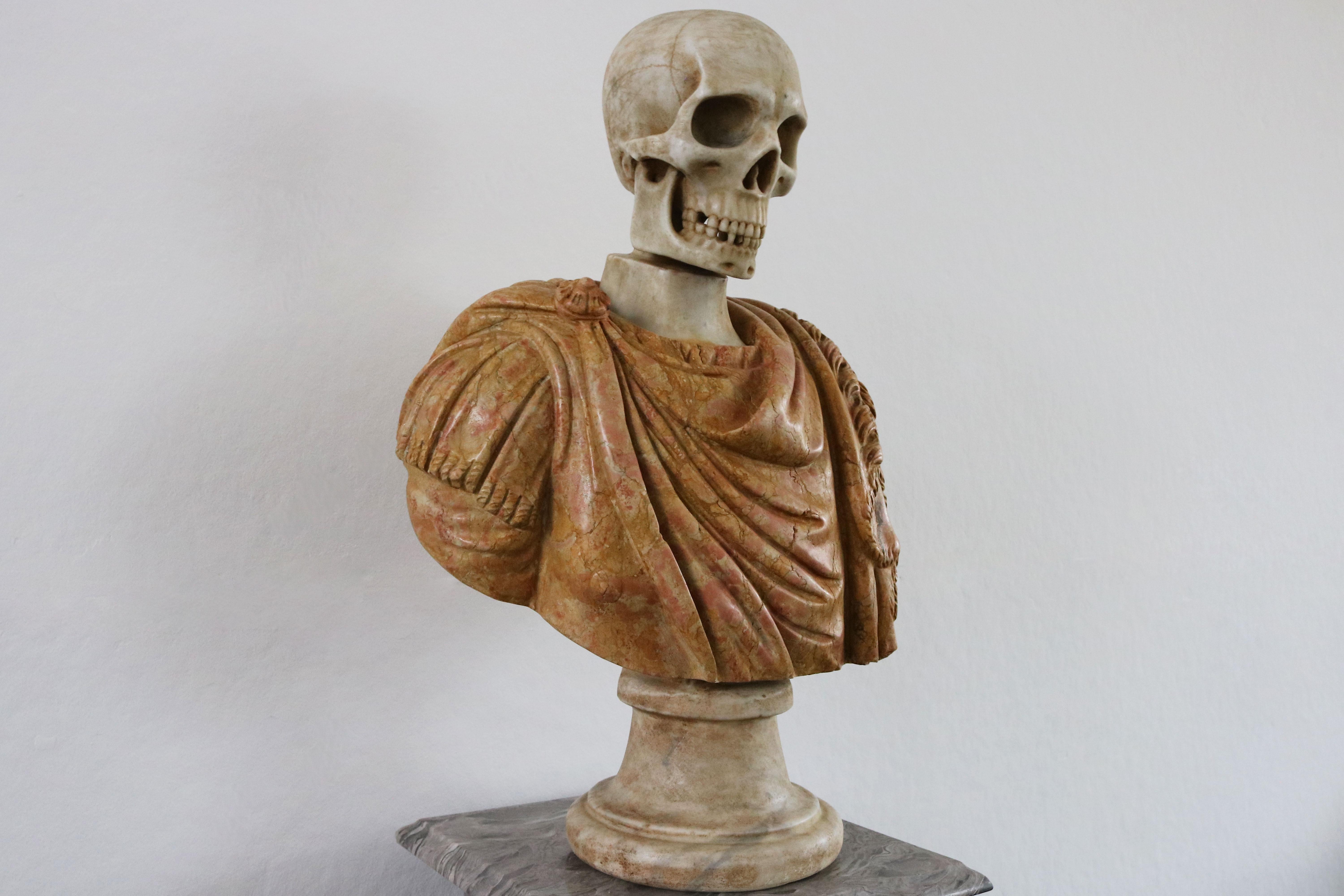 Masterfully carved Italian Vanitas bust in solid marble from late 19th century. 
White Carrara marble skull combined with a red Rosso Imperiale marble Roman toga (robe). 
The roman toga shows gorgeous detail like curves / folds in the fabric & a