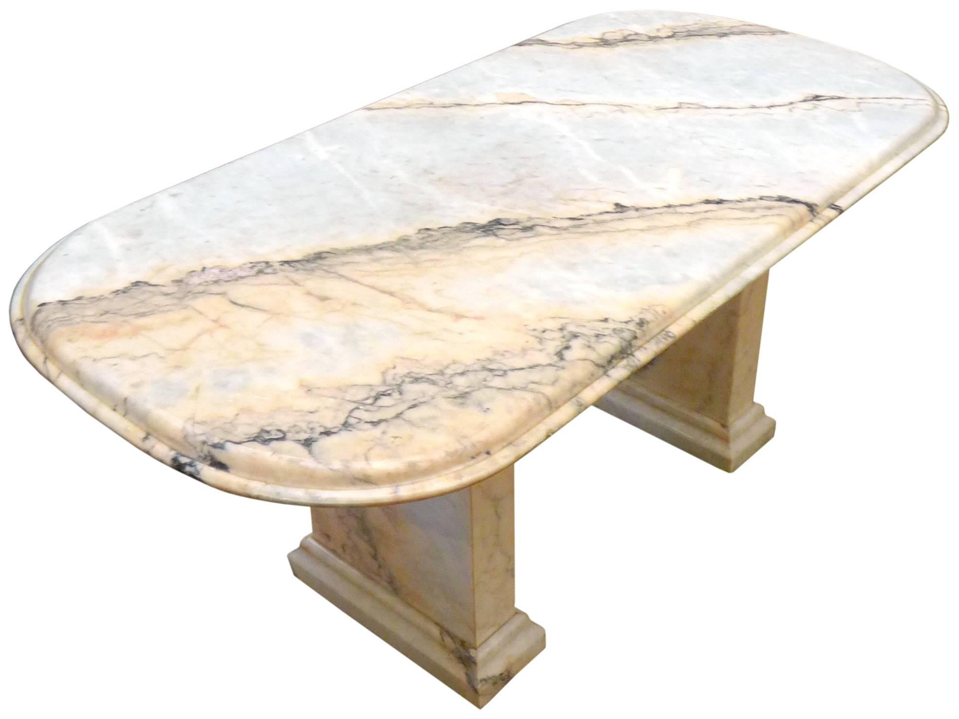 A massive and impressive Italian marble dining table. An aesthetic fusion of classical and modern forms, beautifully executed in rich, figured stone. A dual-pedestal leg structure supports a single-slab, radiused rectangular and double-beveled top.