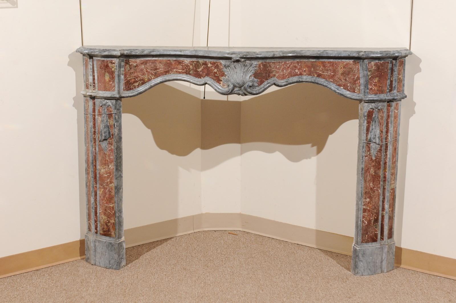 A 18th century Italian marble fireplace surround in grey and salmon hues featuring serpentine form top and shell carving on apron. 

 