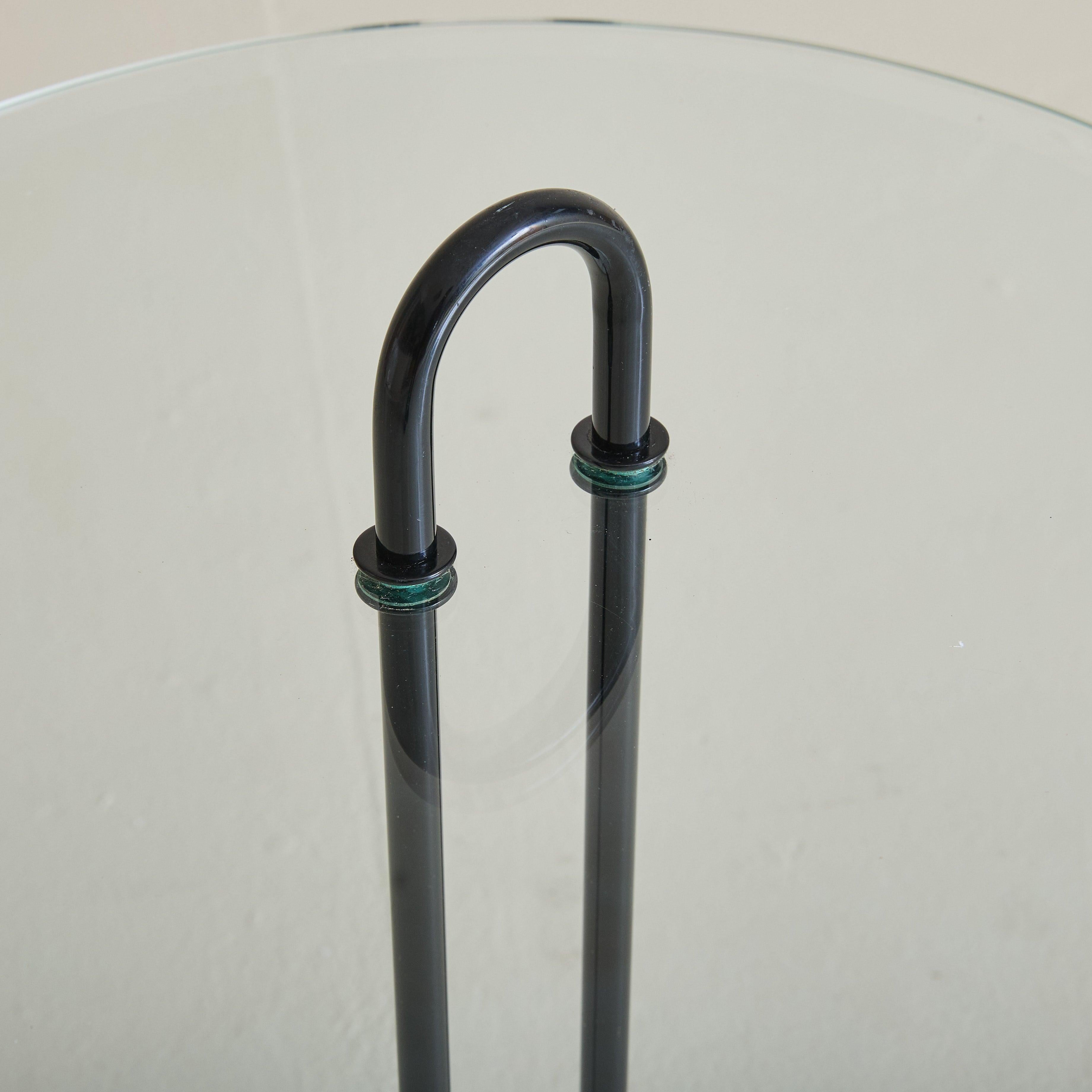 Vendus et tarifés individuellement.

Table d'appoint moderne italienne des années 1980 attribuée à Vico Magistretti pour Cattelan Italia. La table présente un cadre minimaliste en acier laqué noir avec un détail arqué gracieux, supportant élégamment