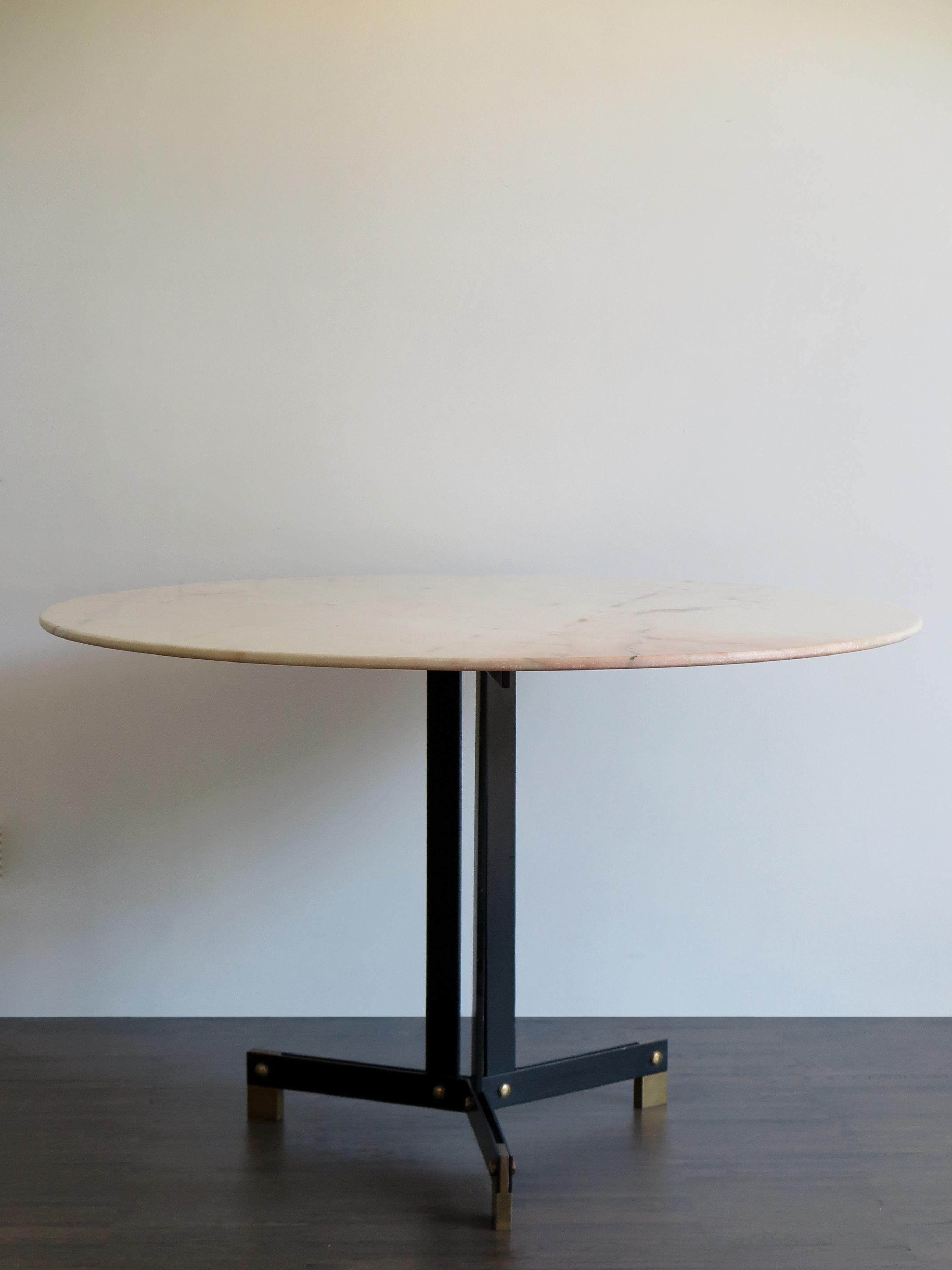 Italian Mid-Century Modern design dining table with round Candoglia marble top and black laquared metal frame and brass feet and details, Ignazio Gardella attributed, Italy circa 1950.
The marble top rests on the metal structure.

Please note